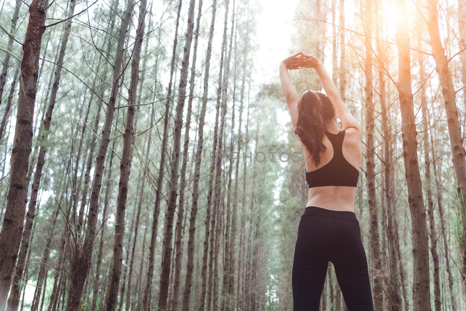 Women stretching arms and breathing fresh air in middle of pinewood forest while exercising. Workouts and Lifestyles concept. Happy life and Healthcare theme. Nature and Outdoors theme. Back view by MiniStocker