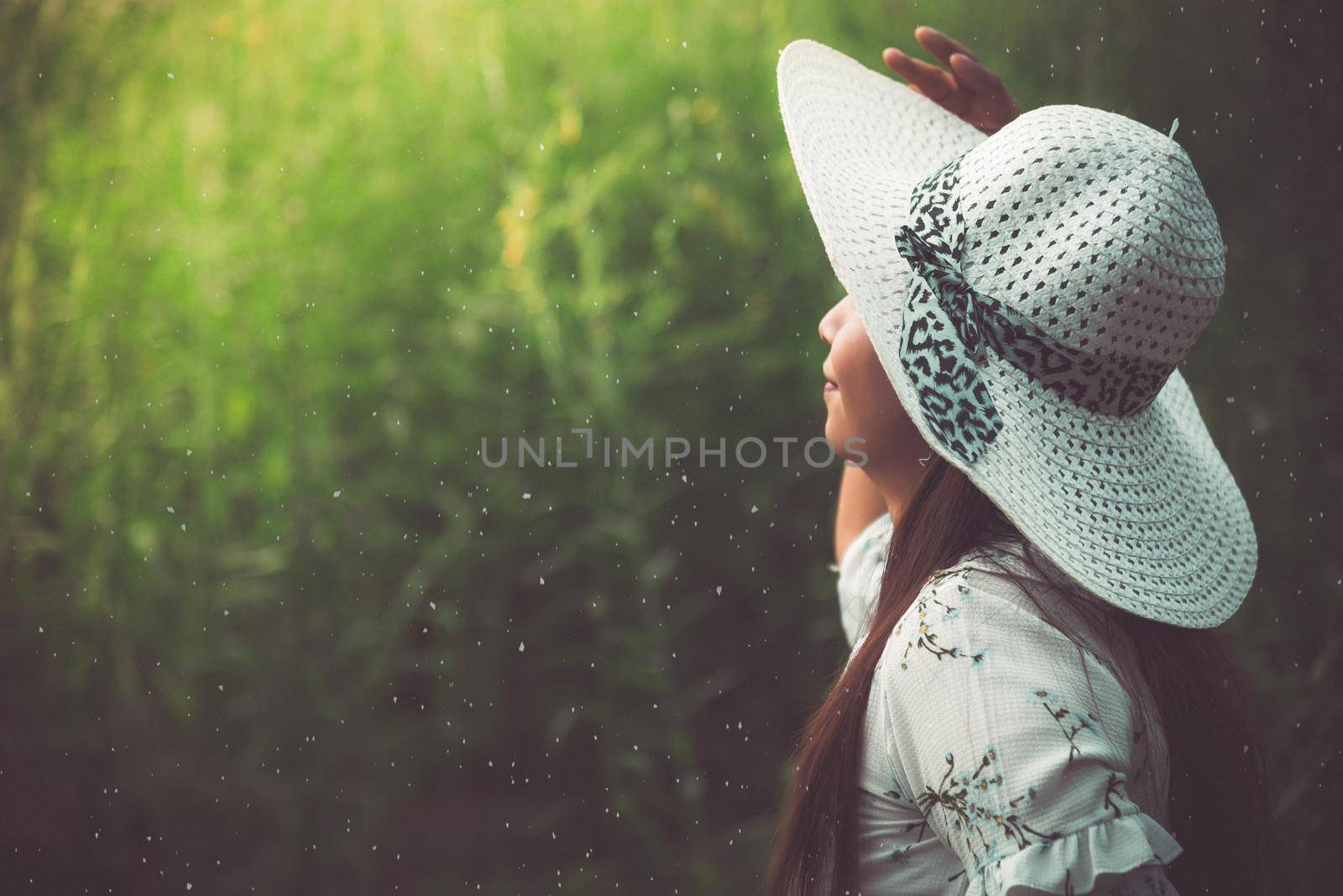 Close up of beauty woman with white dress and wing hat in the meadow background. Beauty and fashion concept. Nature and Travel theme. Back view of woman in forest. Vintage tone film.