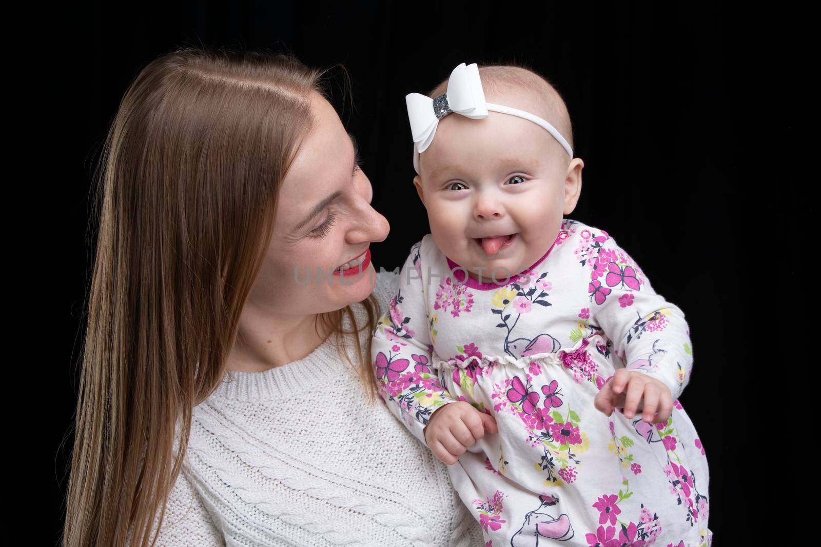 Mom holds a little happy daughter in her arms. Motherhood.