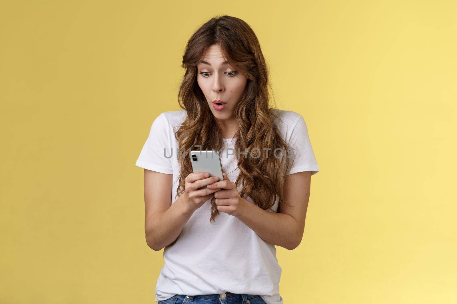 Shocked amazed european girl female blogger become famous online gasping astonished stare camera surprised impressed reading rumors internet social media stand yellow background by Benzoix