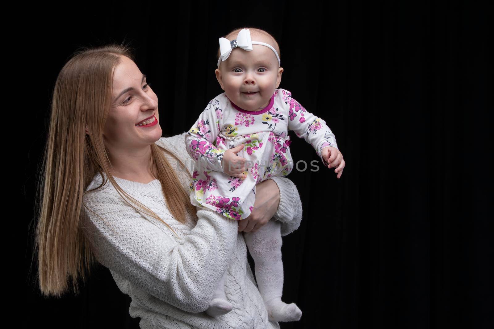 MomMom holds a little happy daughter in her arms.