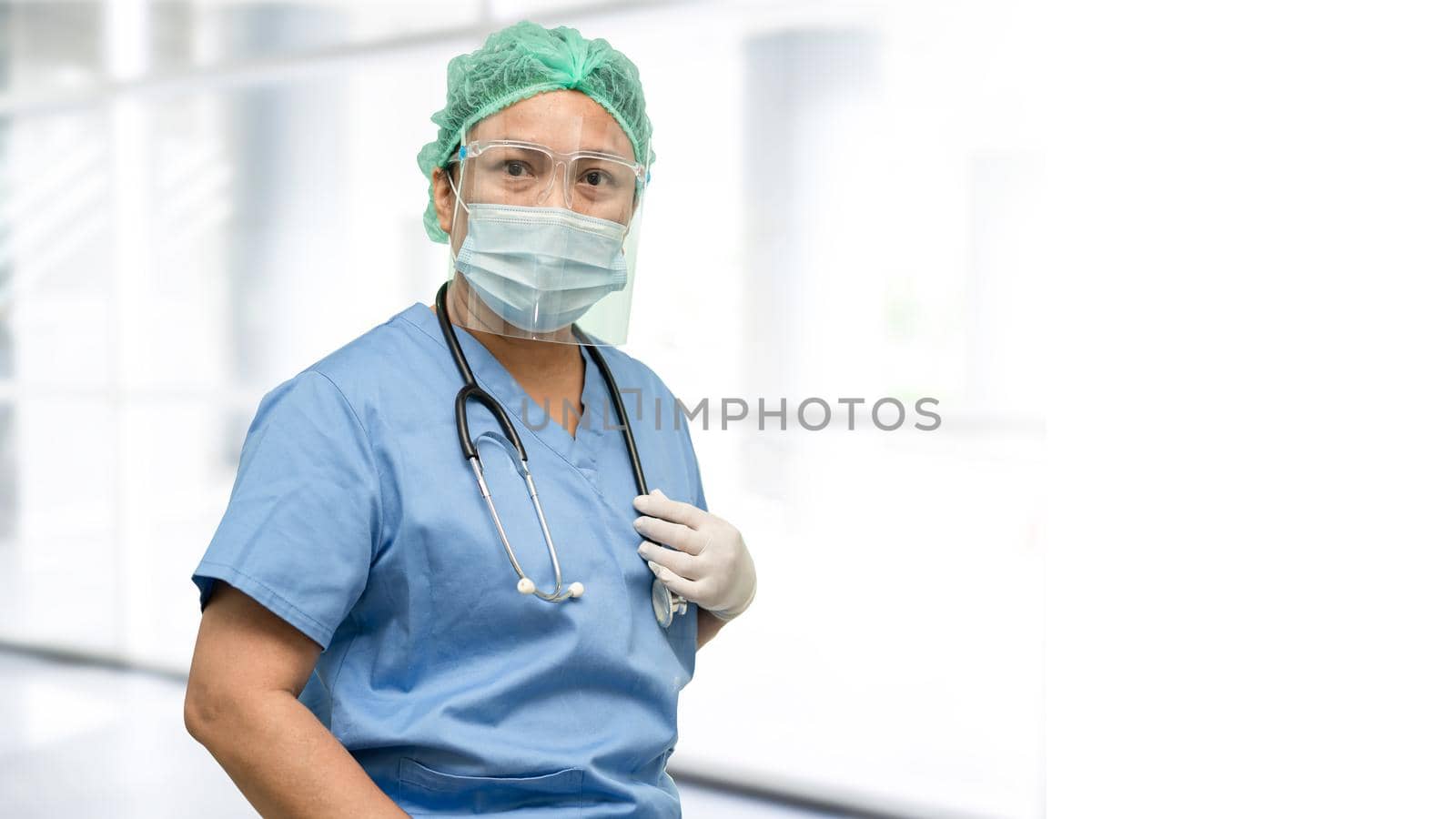 Asian doctor wearing face shield and PPE suit new normal to check patient protect safety infection Covid19 Coronavirus outbreak at quarantine hospital with copy space.