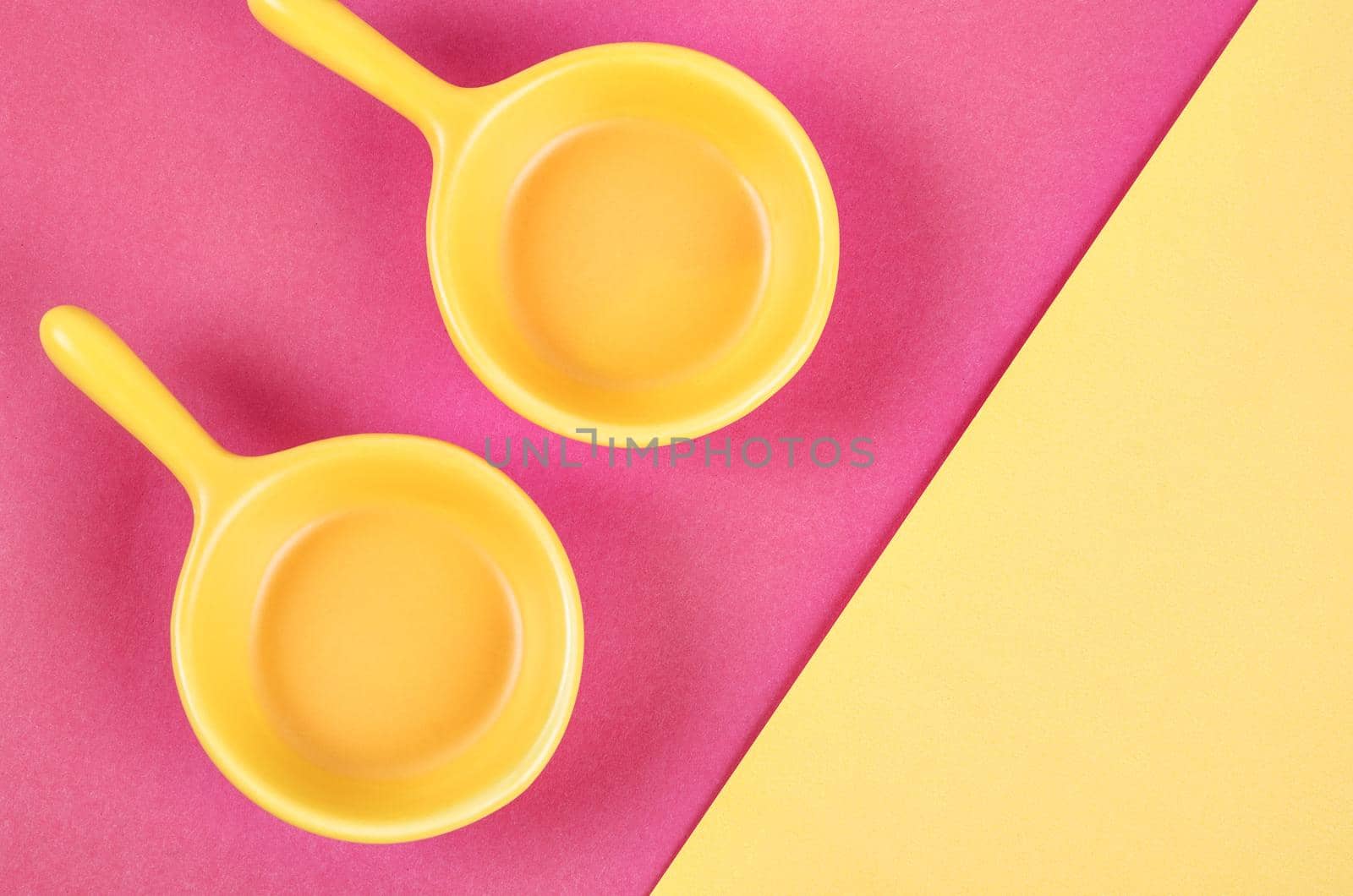 Empty yellow cups on pink and yellow background.