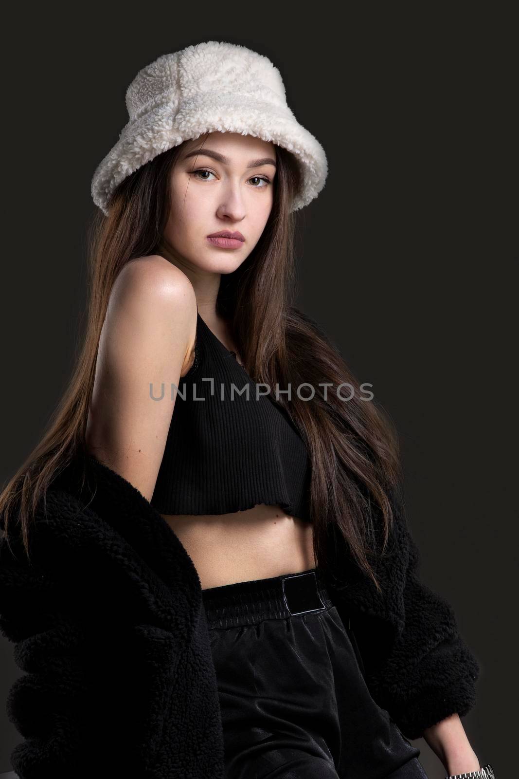 A beautiful girl in a fashionable Panama fur hat looks at the camera.