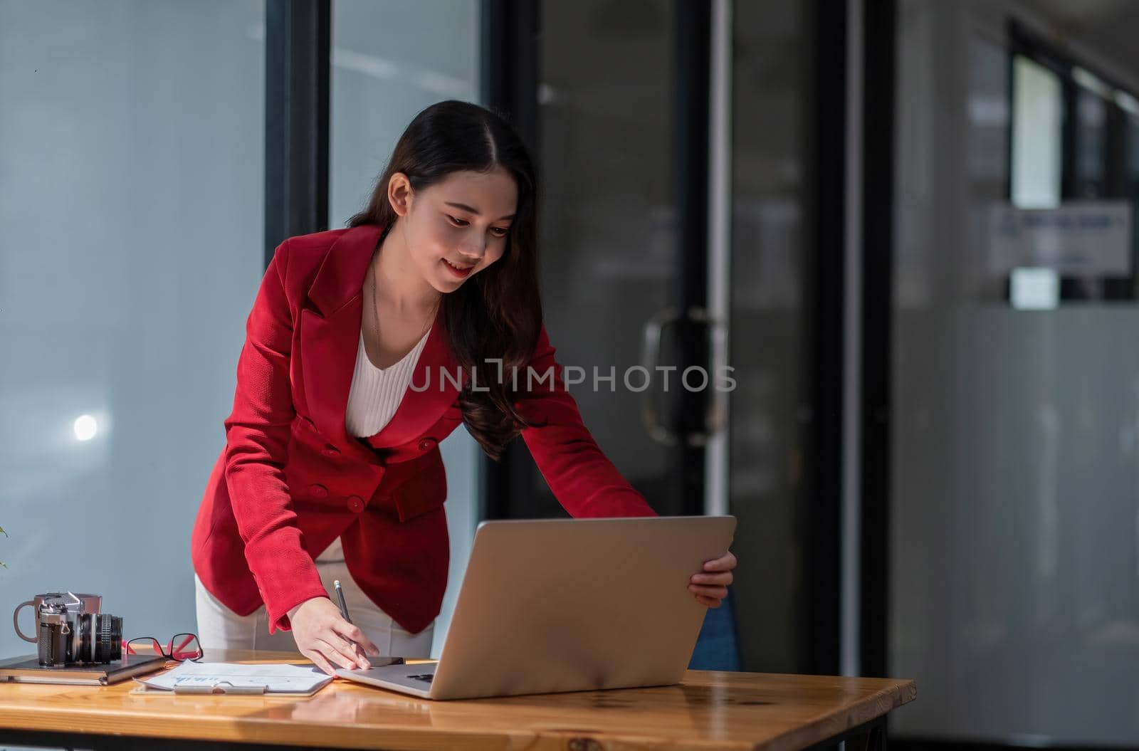 Charming asian woman standing while using laptop computer, female working for financial accounting by nateemee