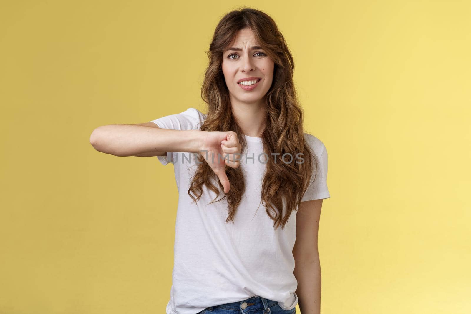 So lame you loser. Ignorant snobbish good-looking woman give own judgement negative opinion disagree grimacing cringe dislike show thumb down disappointed unimpressed yellow background.