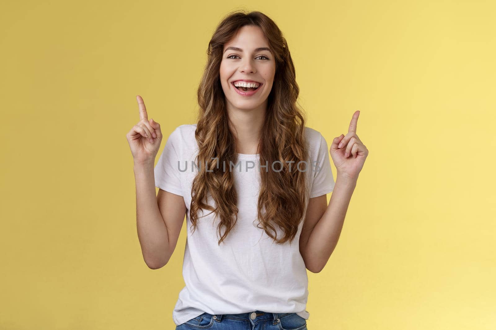 Charismatic enthusiastic attractive lively woman having fun enjoy awesome night out party laughing joyfully pointing up index fingers up introduce promo smiling happily yellow background.