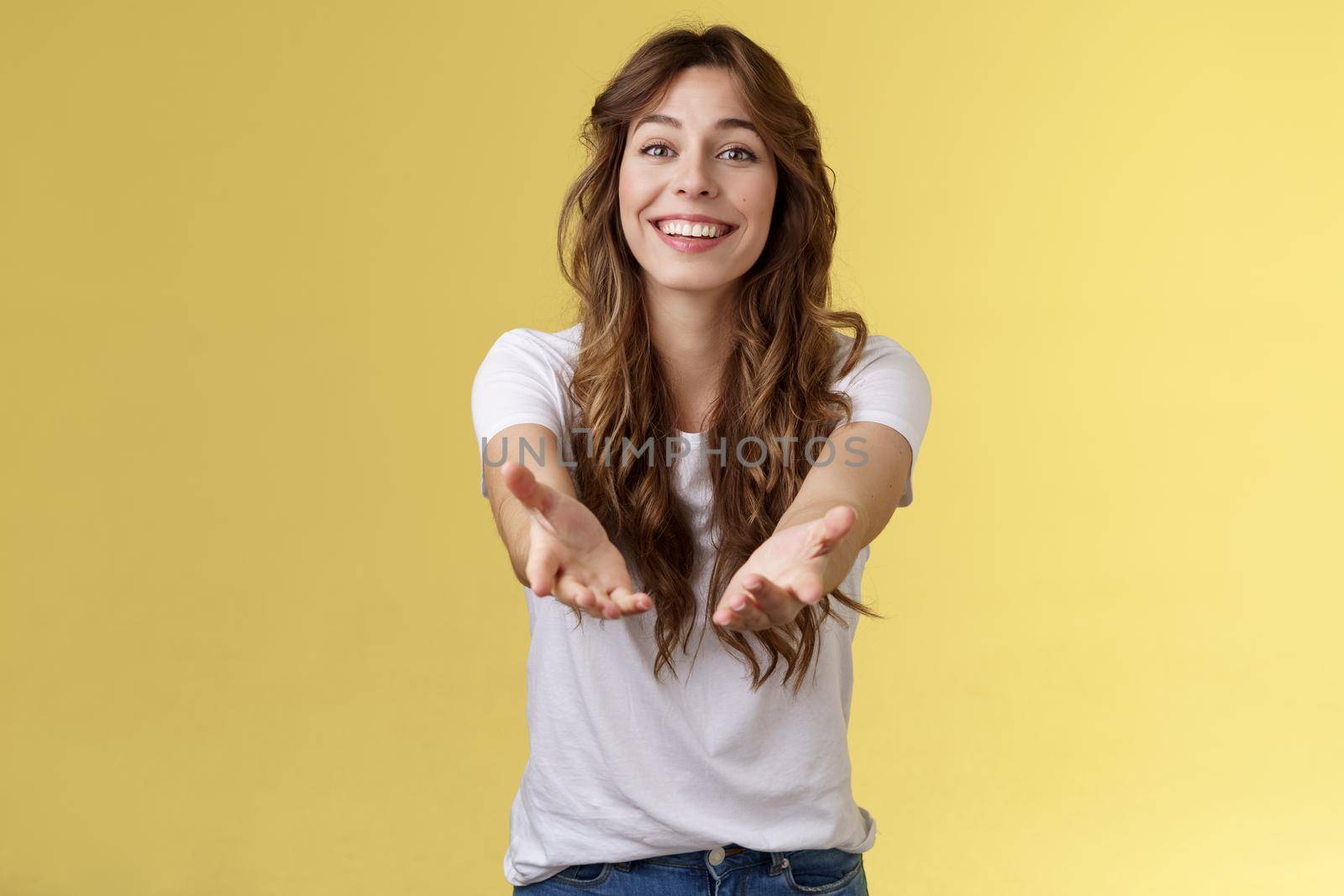 Let me hold it. Sincere tender touched charming curly-haired girl reaching you extend arms smiling lovely tempting grab precious thing receive gift stand yellow background grateful cheerful.