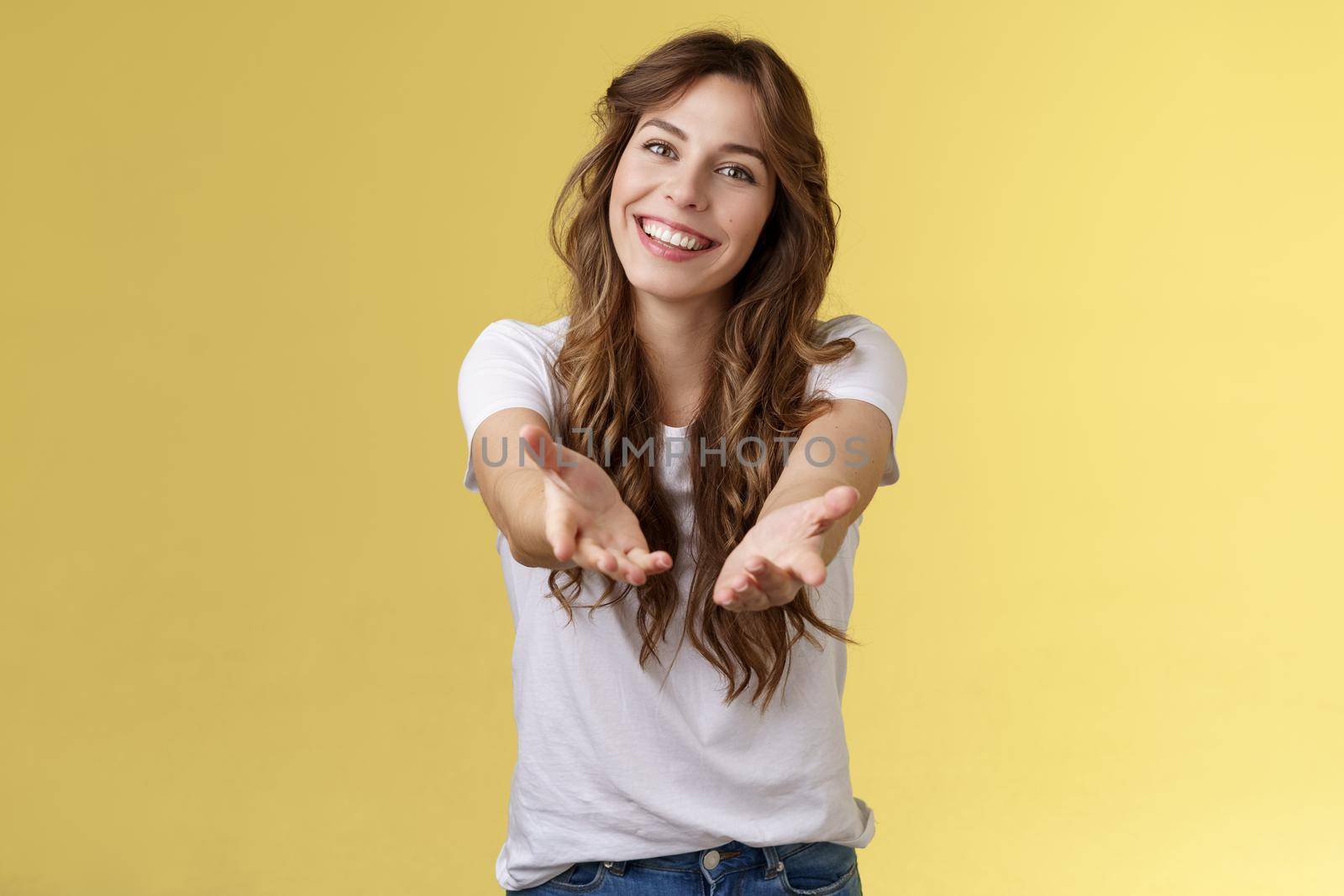 Come closer take my hand. Cheerful lovely charismatic tender woman extend arms forward camera wanna hold receive charming gift tilt head smiling pleased grateful stand yellow background by Benzoix