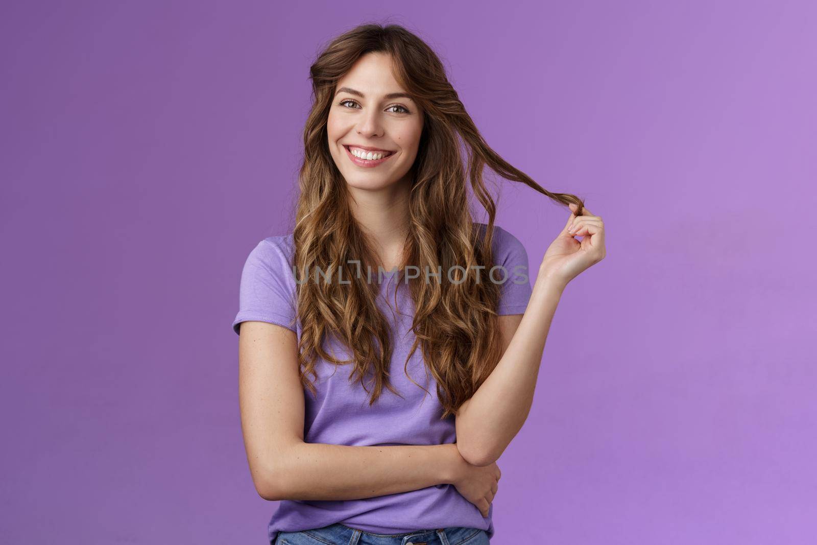Tender confident good-looking outgoing curly-haired girl playing curl touch strand hair smiling enthusiastic hairstylist prepare good look evening date tilt head joyfully grinning cross arm chest. Lifestyle.