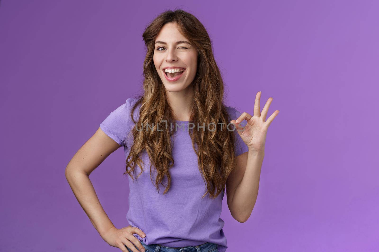 Okay got it. Cheeky flirty girlfriend winking coquettish show alright okay ok sign smiling broadly reassure friend outfit awesome express approval agree good idea stand purple background pleased.