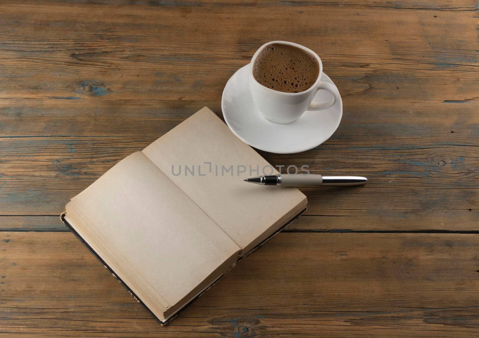 top view image of open book with blank pages next to cup of coffee on wooden table. ready for adding text or mockup