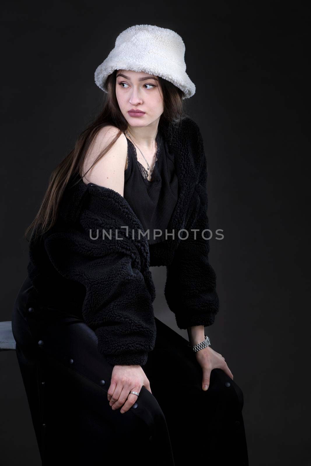 Beautiful stylish girl in a fur hat on a dark background.