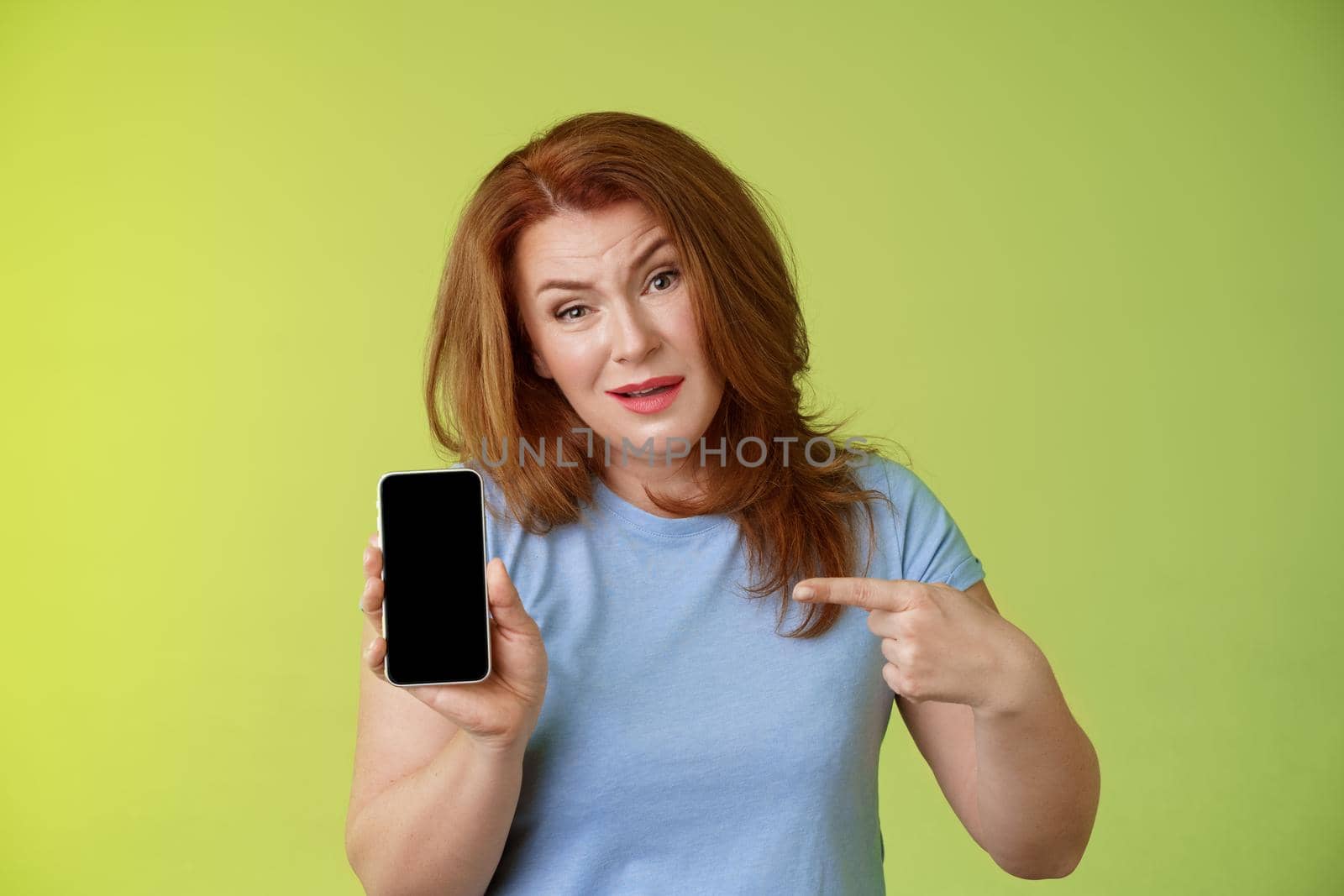 Have something say. Questioned serious-looking displeased redhead mature mother acting pissed hold smartphone pointing blank mobile phone screen demand answers found daughter social-media photos by Benzoix