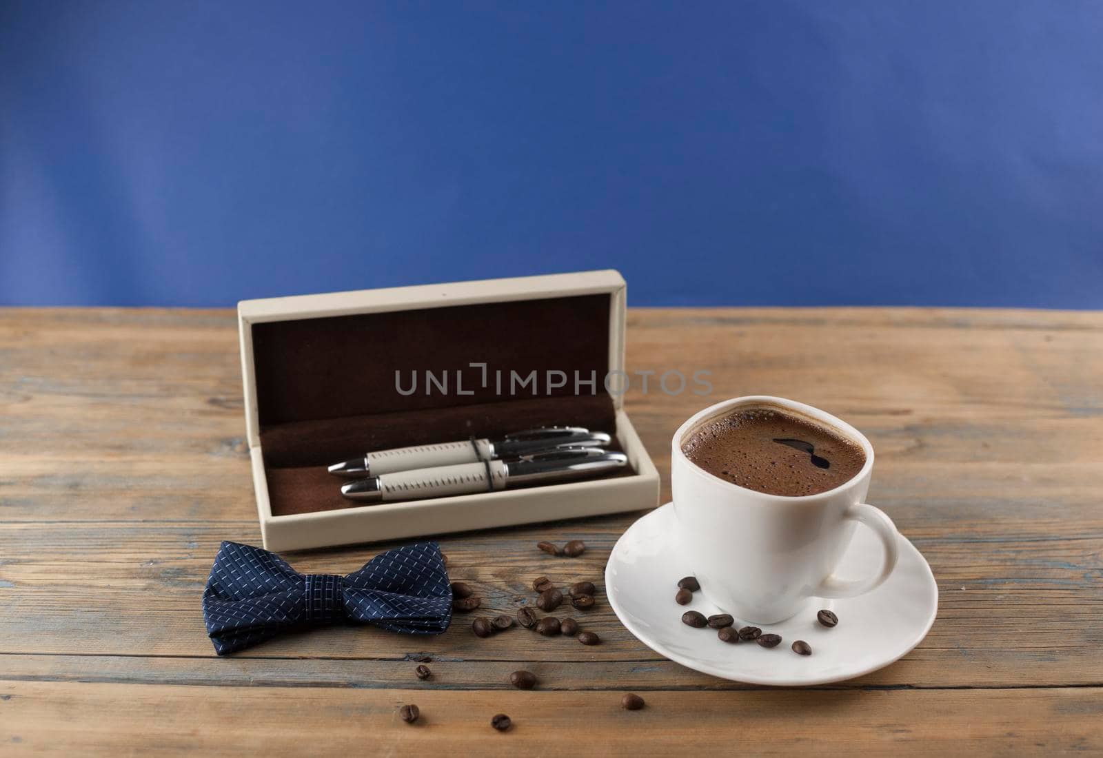 A cup of coffee with bow tie and gift box on old wooden table with some beans. Father day card. by inxti