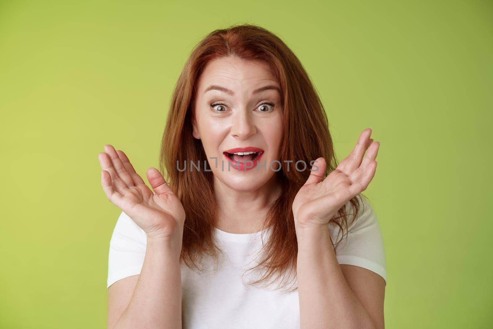 Glad surprised happy redhead middle-aged mother surprised gasping clap hands impressed wide gaze smiling broadly amazed unexpected family visit cheering positive news receive lucky chance celebrating by Benzoix