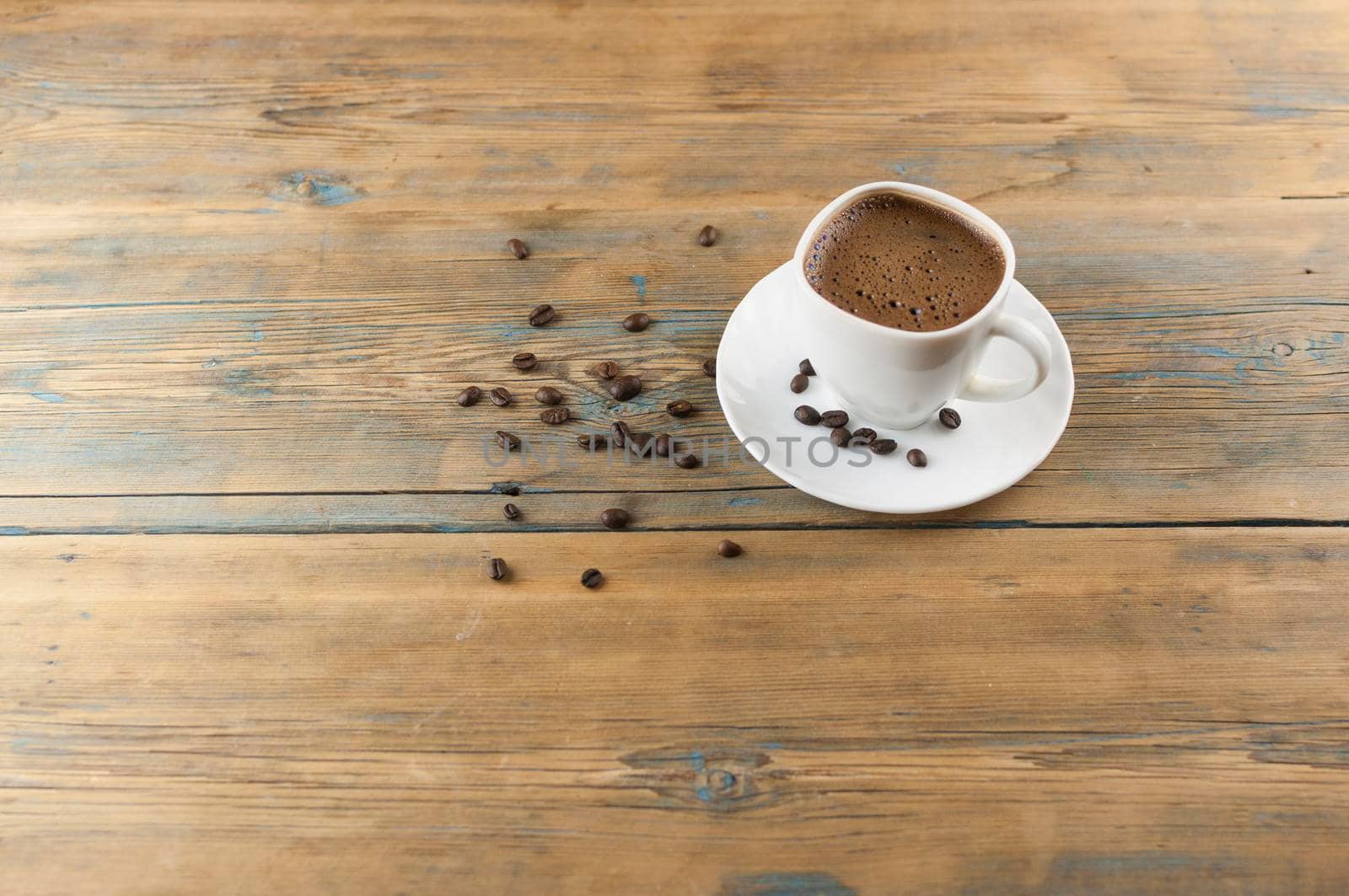 A cup of coffee on old wooden table with some roasted beans