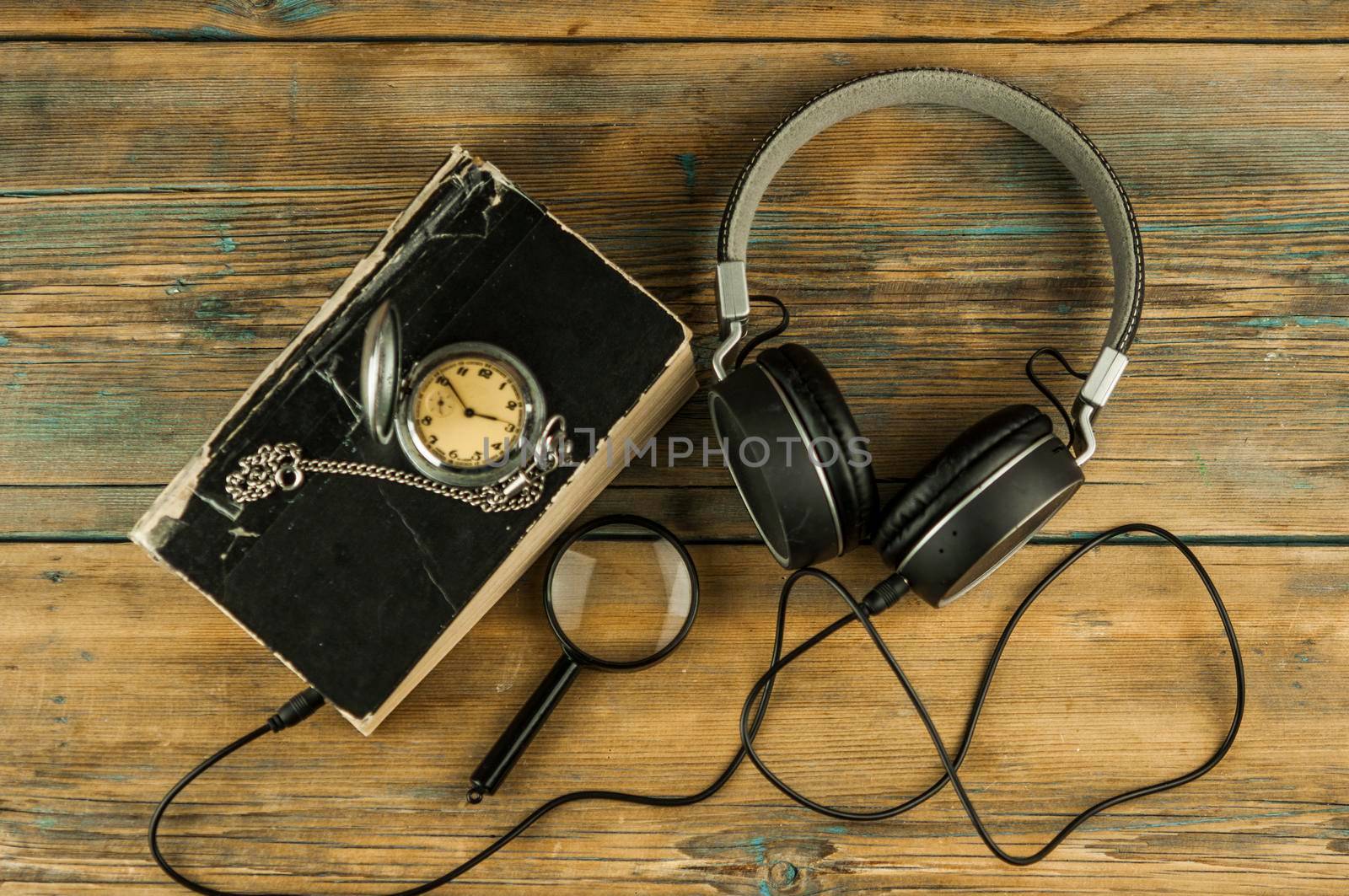 Black headphones and close book are on the wooden table. Audio book concept. Distance learning