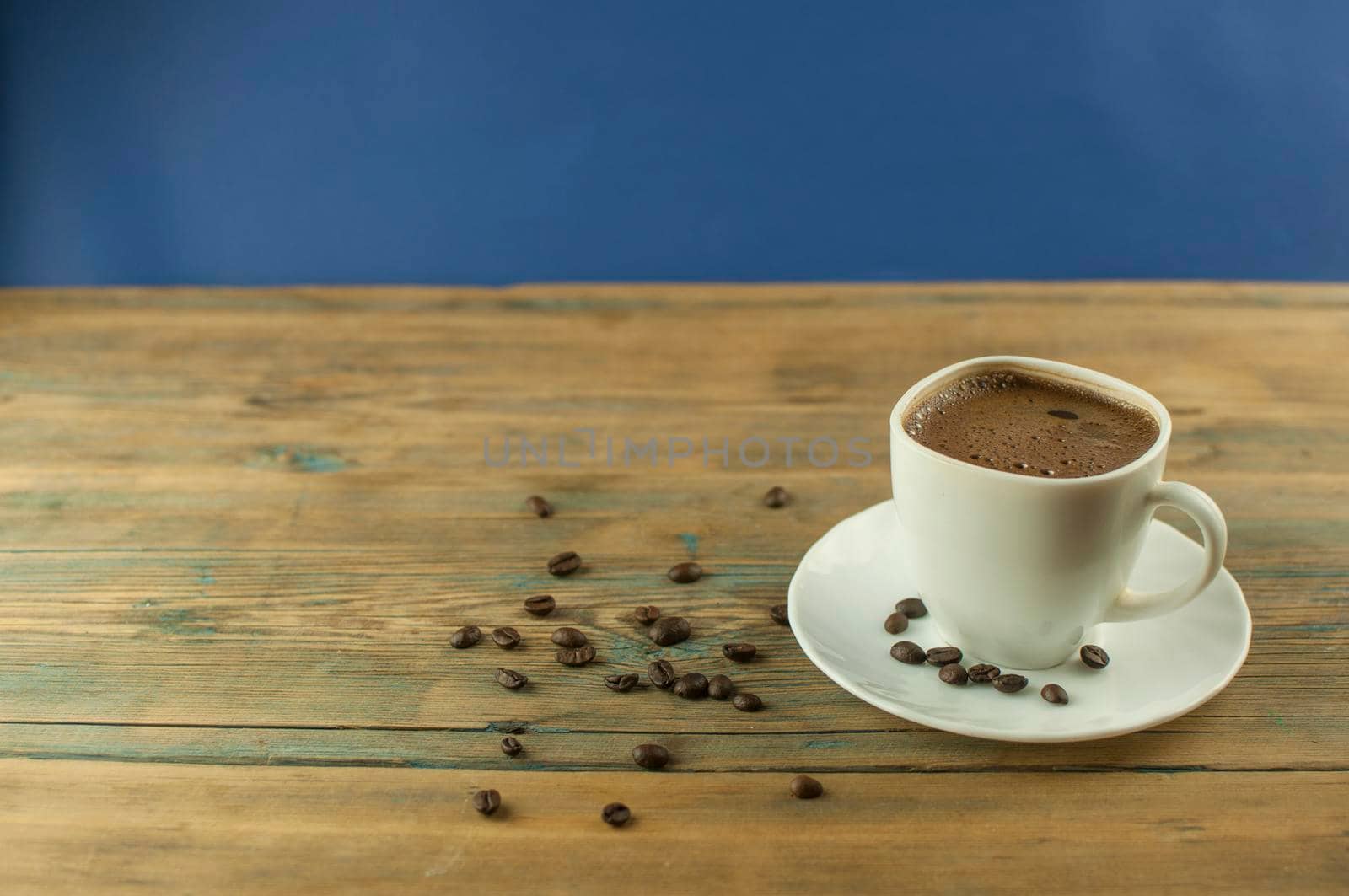 A cup of coffee on old wooden table with some roasted beans