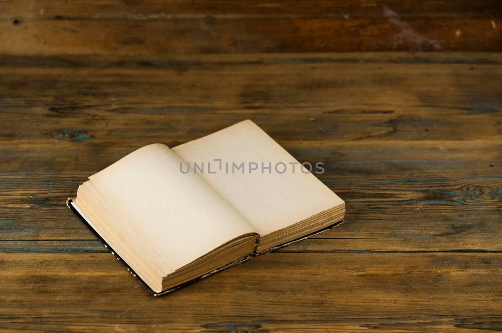 an old open book with blank pages lies on a wooden table