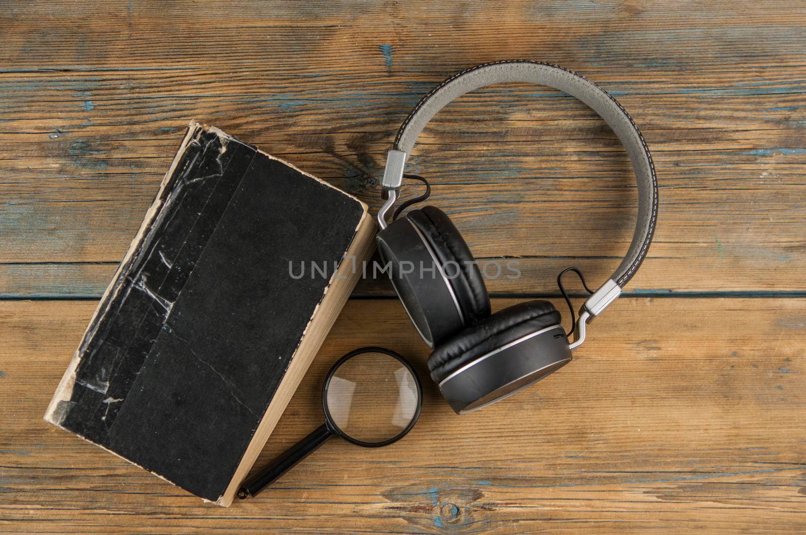 book and headphones on a wooden background. concept of audiobook. by inxti