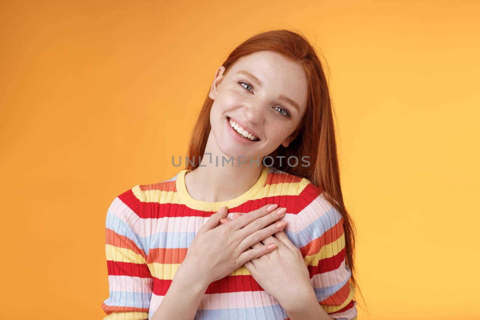 Happy grateful passionate stylish redhead european girl thanking dearest friend lovely sweet gift press palms heart smiling broadly tilting head amused gratefully appreciate, orange background by Benzoix