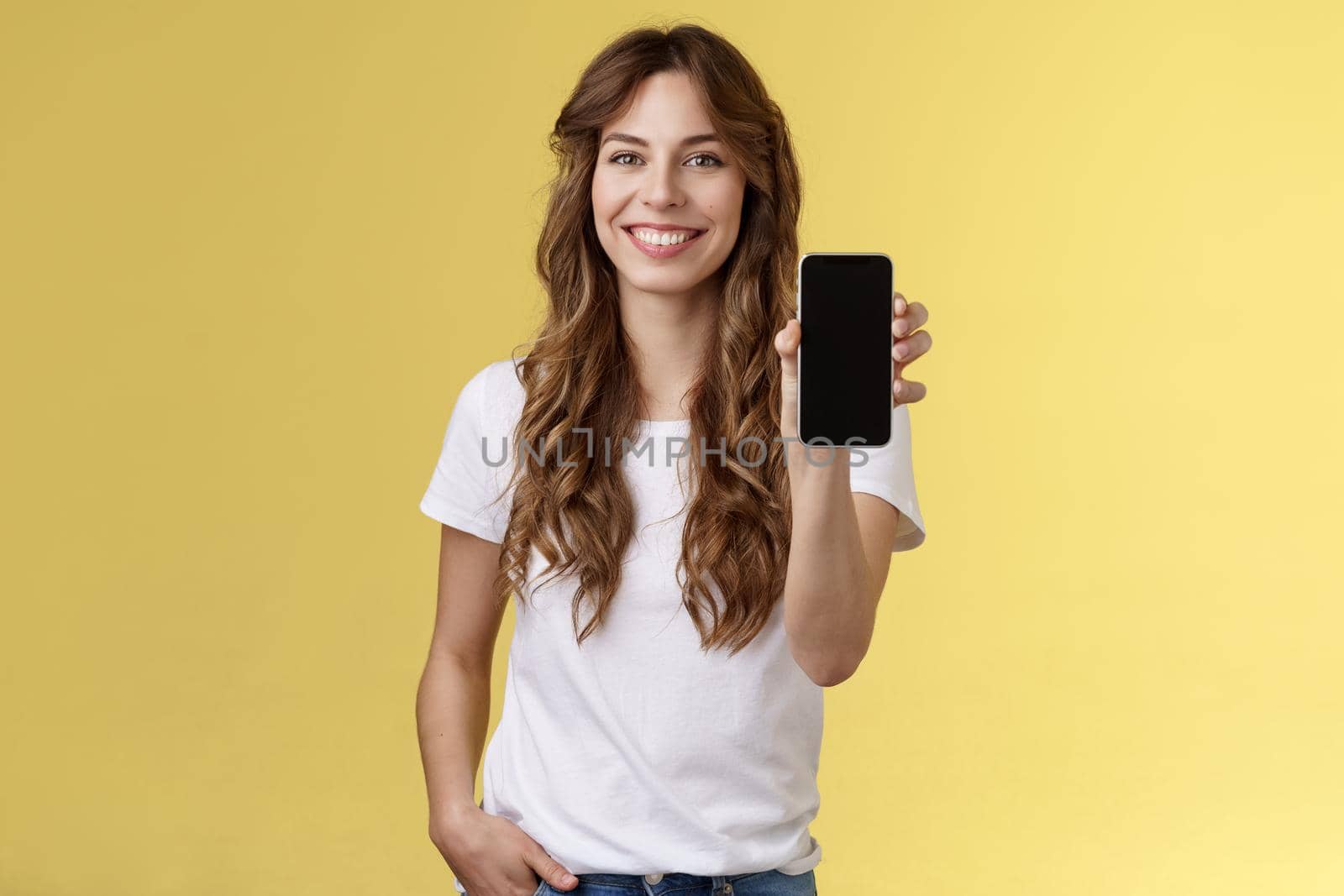 This app all you need. Cheerful friendly outgoing stylish girl showing her smartphone blank mobile phone display camera introduce social media page smiling delighted bragging bank account.