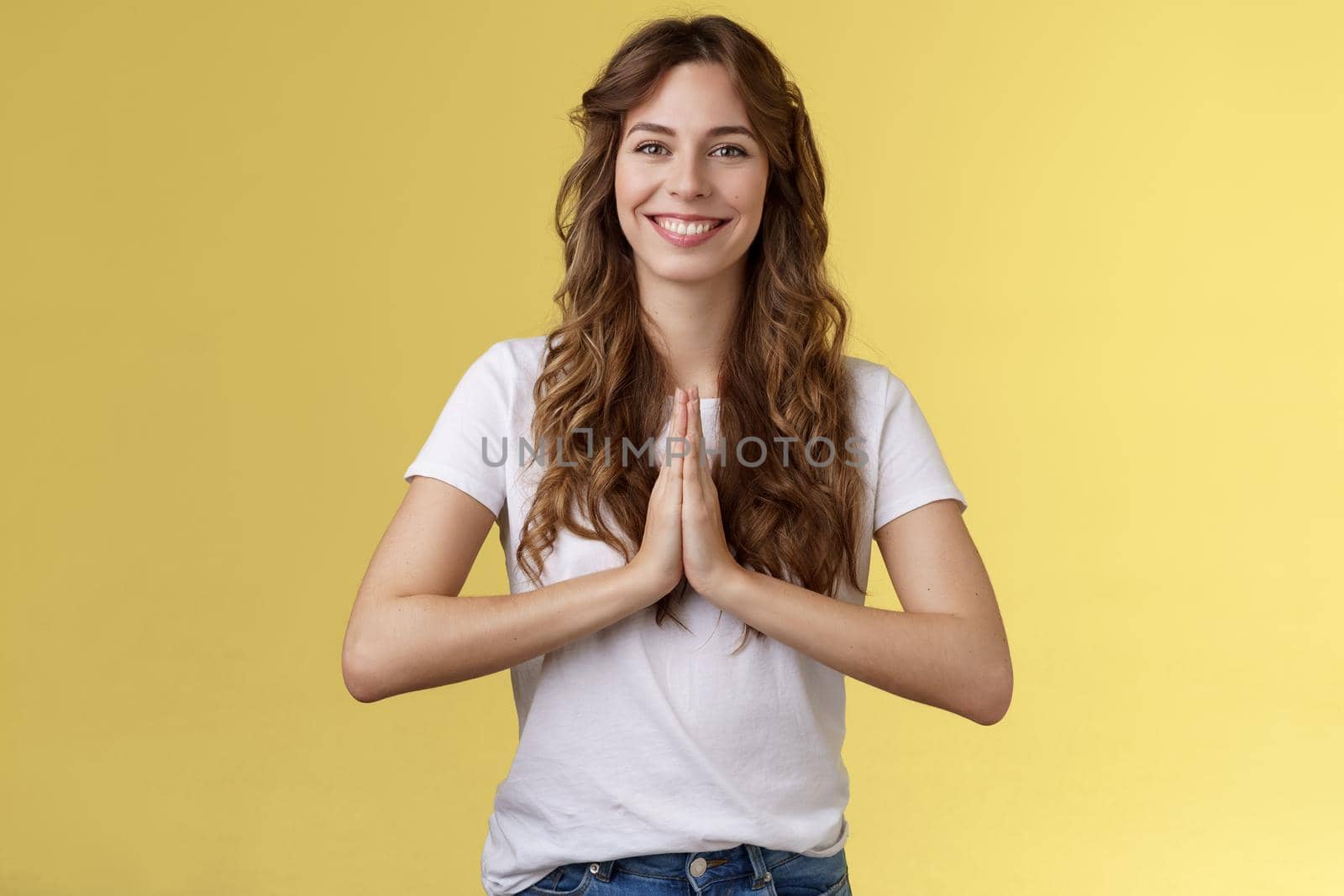 Friendly happy relaxed good-looking woman say namaste smiling broadly relieved feel okay grinning positive vibe press palms together supplication gesture asking offer hopeful yellow background by Benzoix