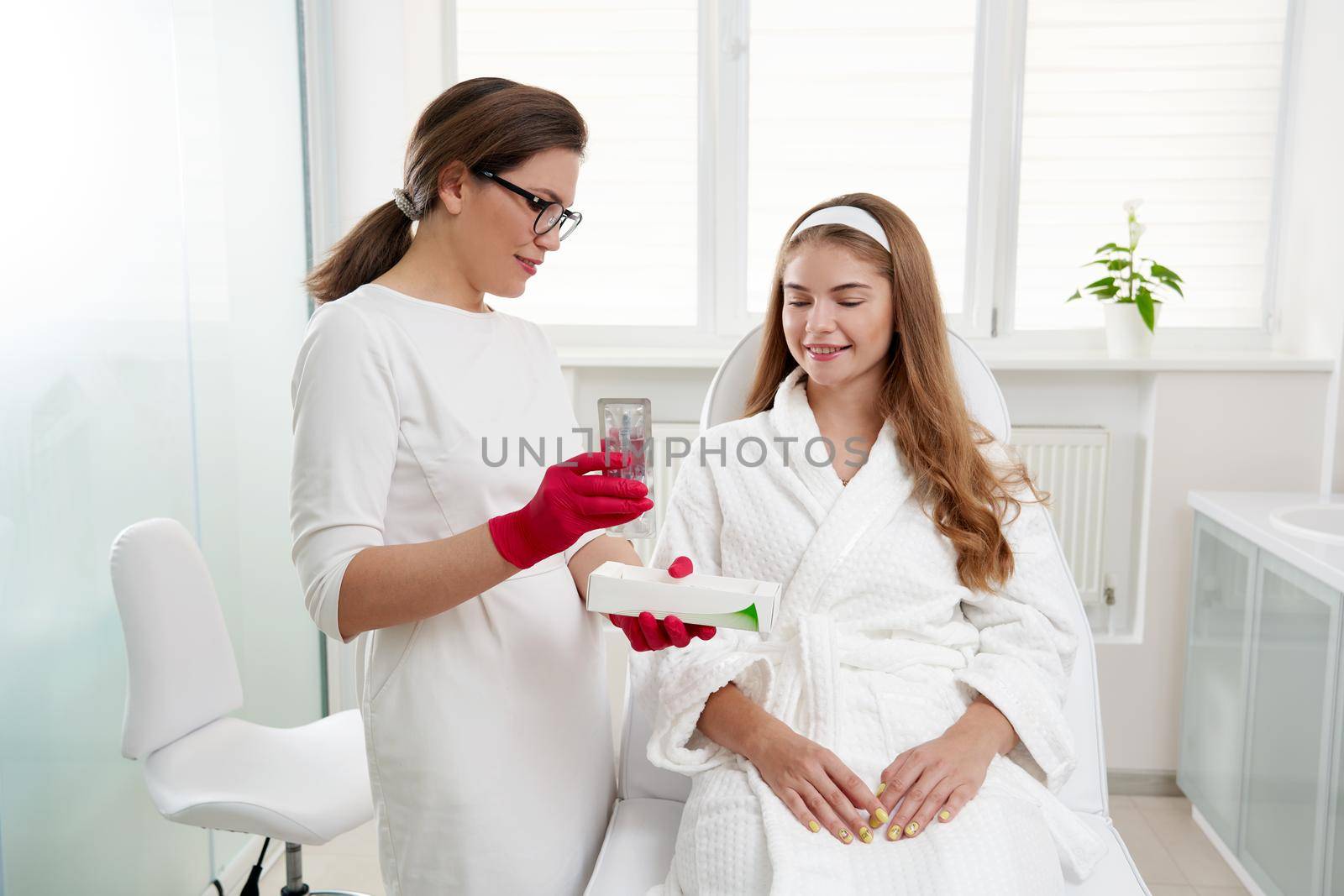 dermatologist shows beautiful young patient cosmetics that are used at spa beauty salon by Mariakray