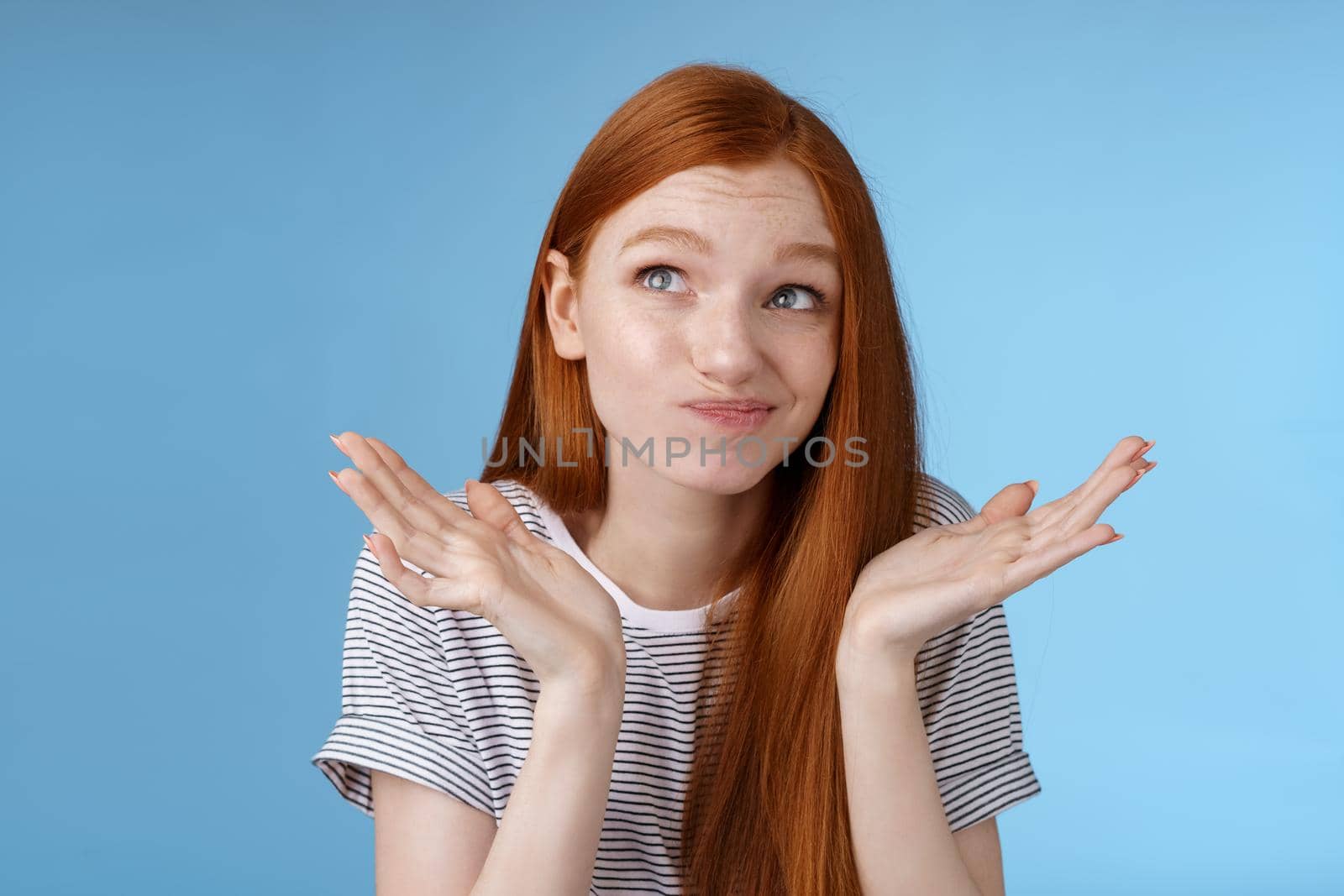 Awkward uncomfortable attractive redhead popular girl trying think up excuse feeling reluctant uncertain standing doubtful shrugging spread hands sideways smirking look up hesitant.