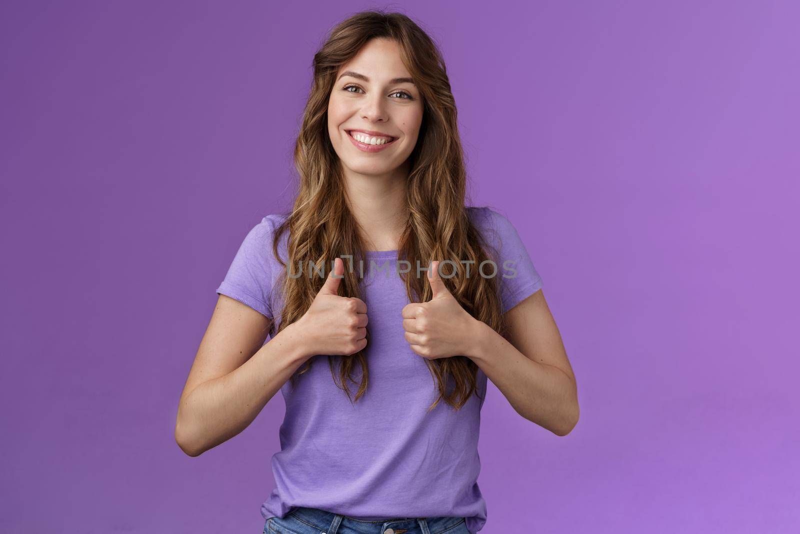 Upbeat positive attractive cheerful curly girl show thumbs up approval sign smiling delighted encourage friend good job well done standing satisfied like positive opinion purple background. Lifestyle.