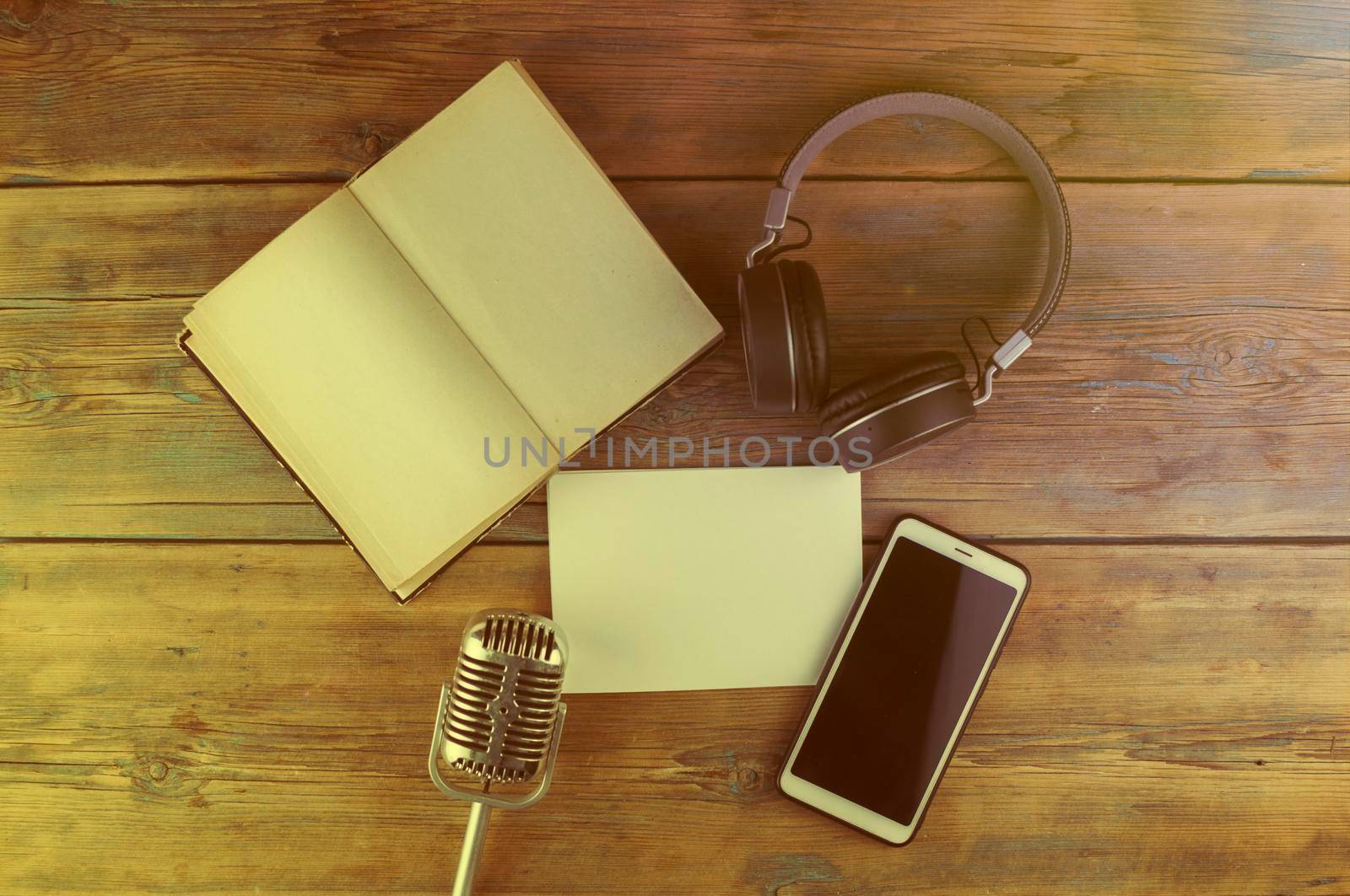 Black headphones with smarphone and open book are on the wooden table. Audio book concept. Distance learning. Close up, copy space, background.