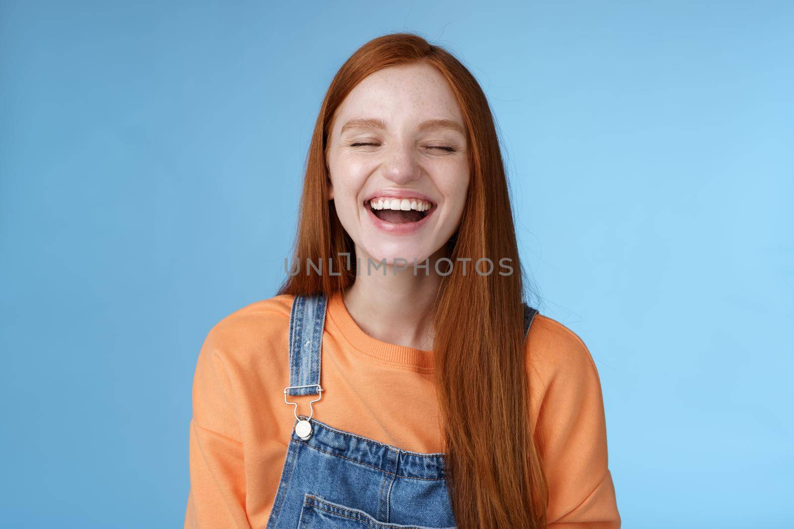 Carefree happy positive lucky redhead girl having fun close eyes smiling optimistic laughing out loud chuckling funny joke listen hilarious stories relaxing hang out friends, blue background by Benzoix