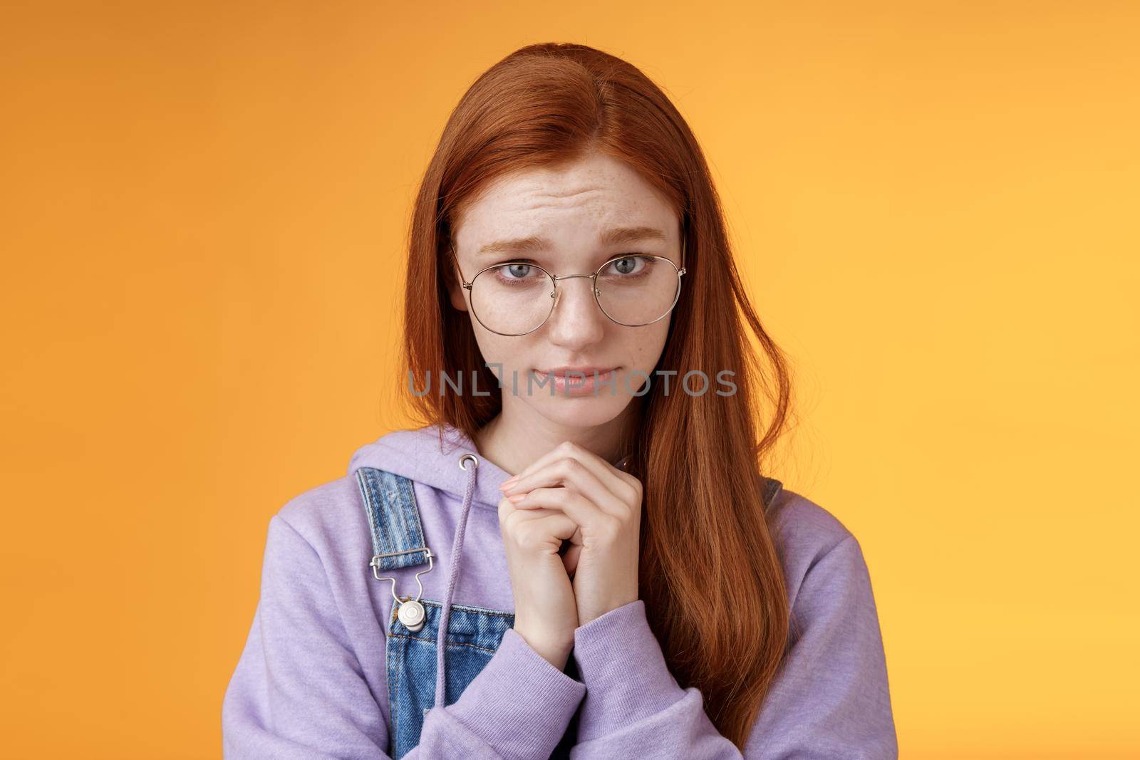 Silly guilty young shy redhead girlfriend asking forgiveness supplicating lower head look from under forehead frowning begging apology favour standing insecure sad pleading help, orange background by Benzoix