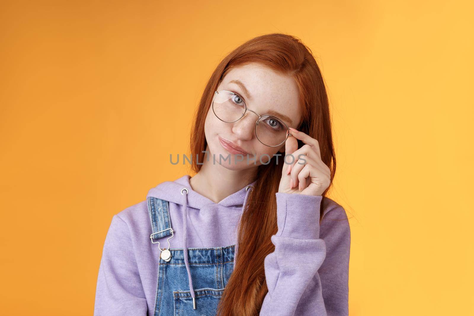 Annoyed bossy unimpressed bothered young redhead female coworker smirking tilting head irritated touch glasses look ignorant cringing stupid uninteresting doubtful story not buy any excuses.