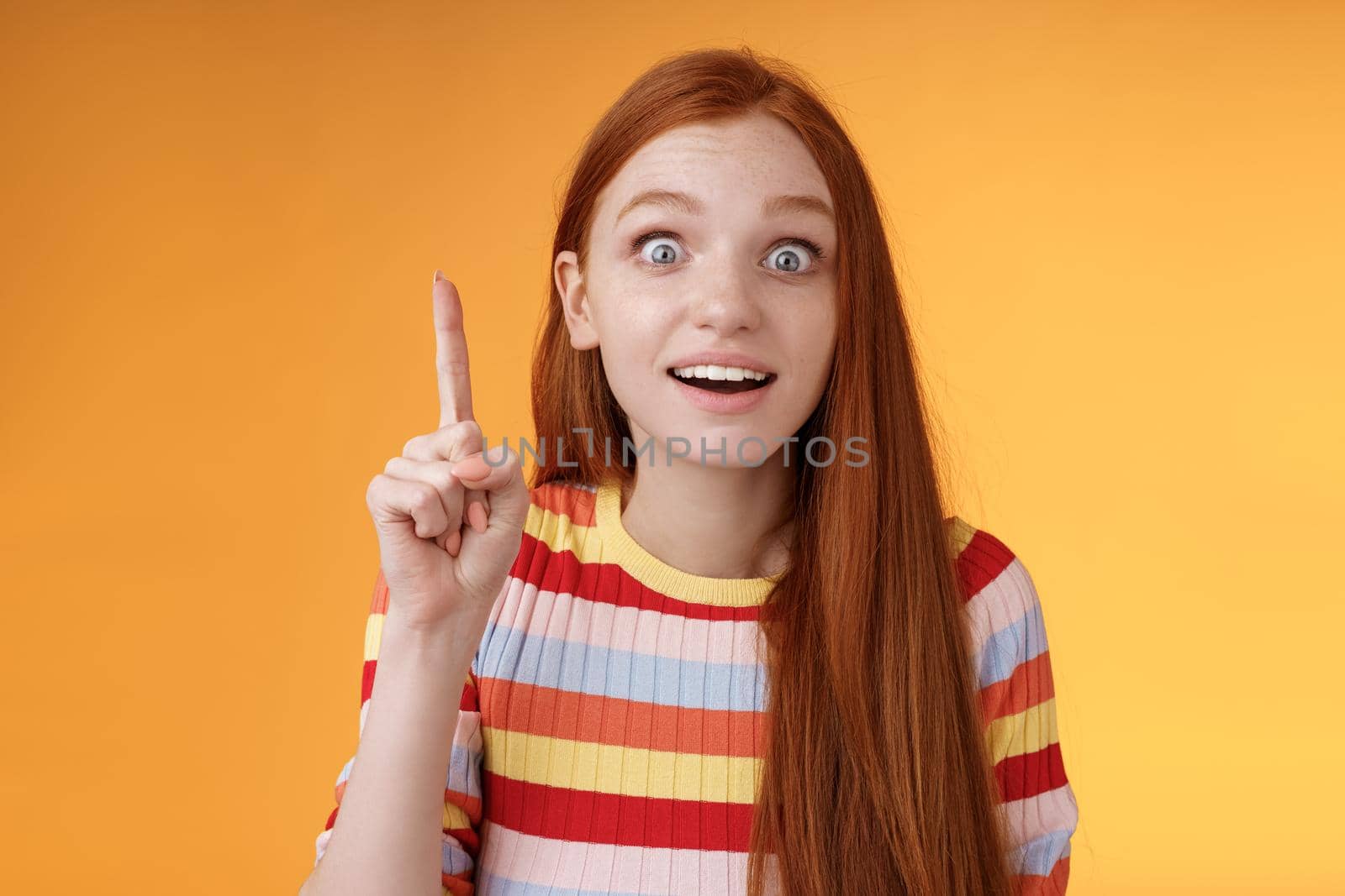 Great idea striked mind. Attractive excited surprised redhead woman open mouth smiling amused raise index finger eureka gesture stare camera shocked found solution have perfect plan by Benzoix