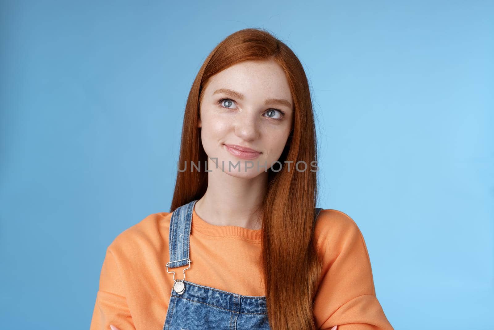 Smart creative pretty redhead female freelancer thoughtfully look upper left corner pondering decision smirking thinking make-up idea standing confident hands crossed chest blue background by Benzoix