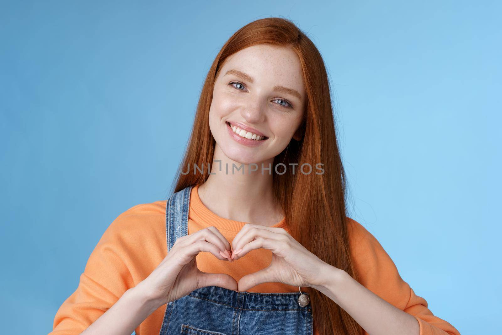 Love you. Attractive romantic tender redhead smiling gentle girlfriend blue eyes freckles show heart chest express sympathy romantic positive attitude confess passionate deep feelings, grinning cute.