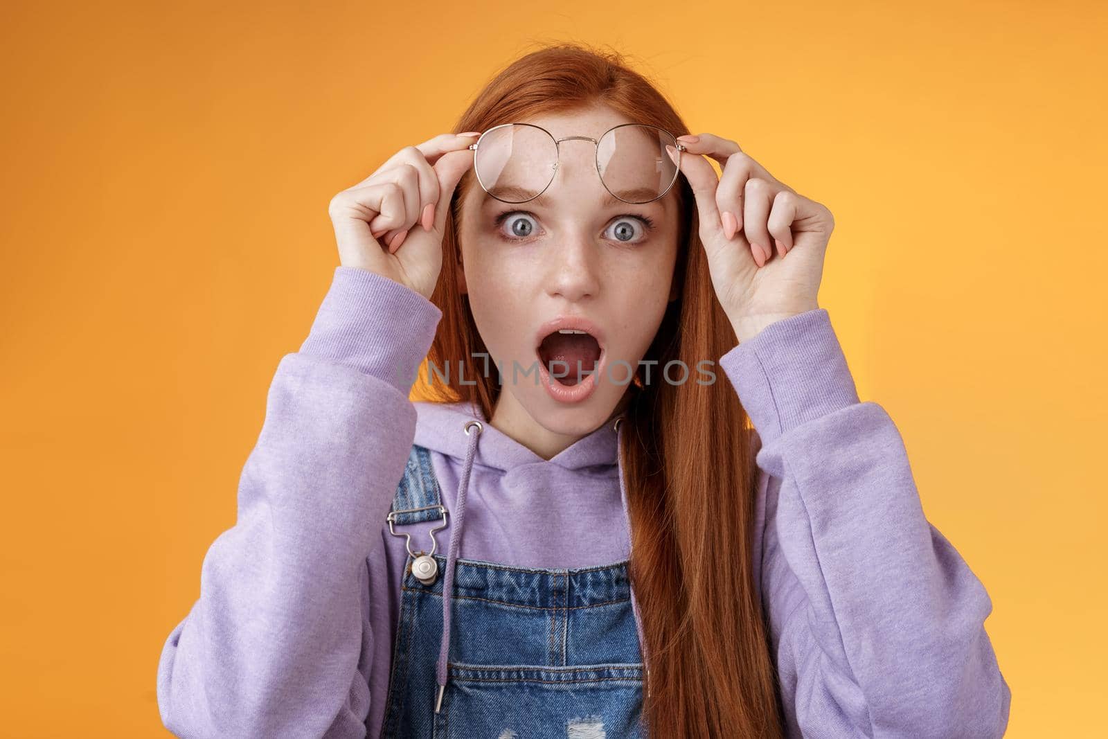 Omg no freakin way. Shocked emotional redhead girlfriend take off glasses speechless drop jaw gasping stunned wide eyes camera stare amazed found out shook secret standing orange background by Benzoix