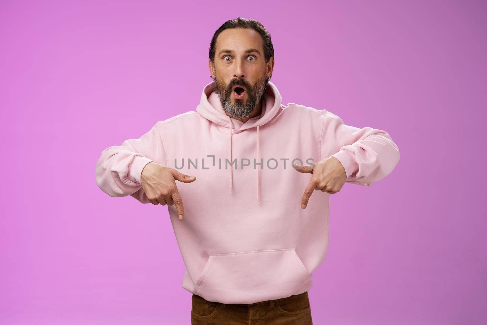 Impressed fascinated speechless dad bearded grey hair say wow widen eyes surprised folding lips amused curiously pointing down index fingers see super amazing advertisement, posing purple background by Benzoix