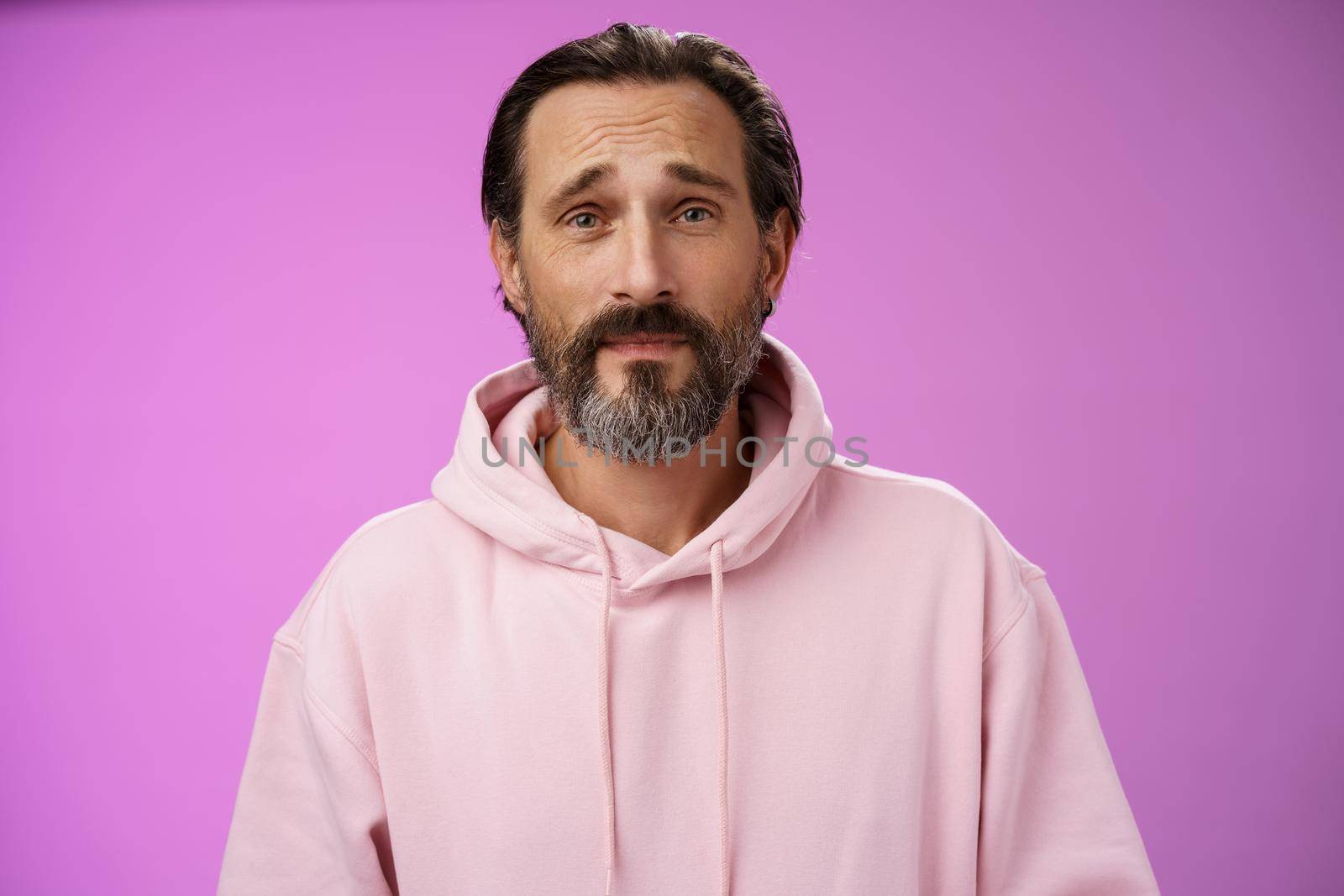 Upset worried unconfident adult bearded caucasian man grey hair frowning look hopefully nervously waiting important news, standing anxious hesitant unhappy, standing purple background unwell.