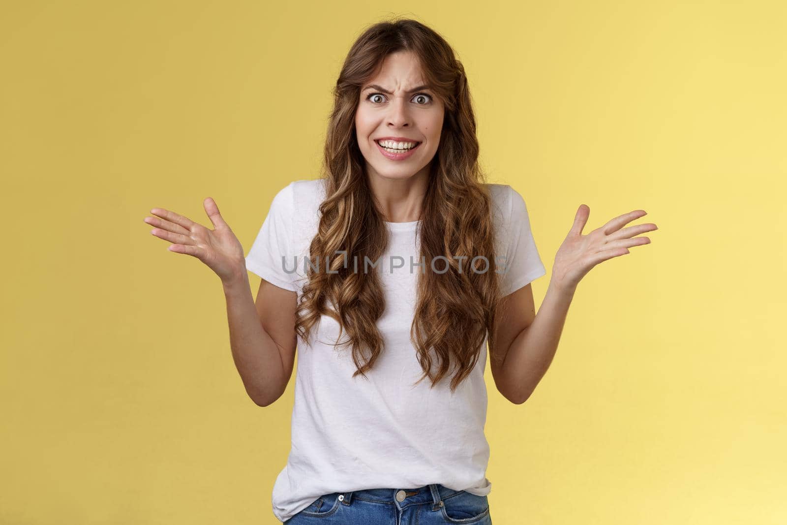 Angry freaked out disappointed woman frowning grimacing anger distress raise hands sideways full dismay complaining being rude arguing look pissed outraged swearing frustrated yellow background.