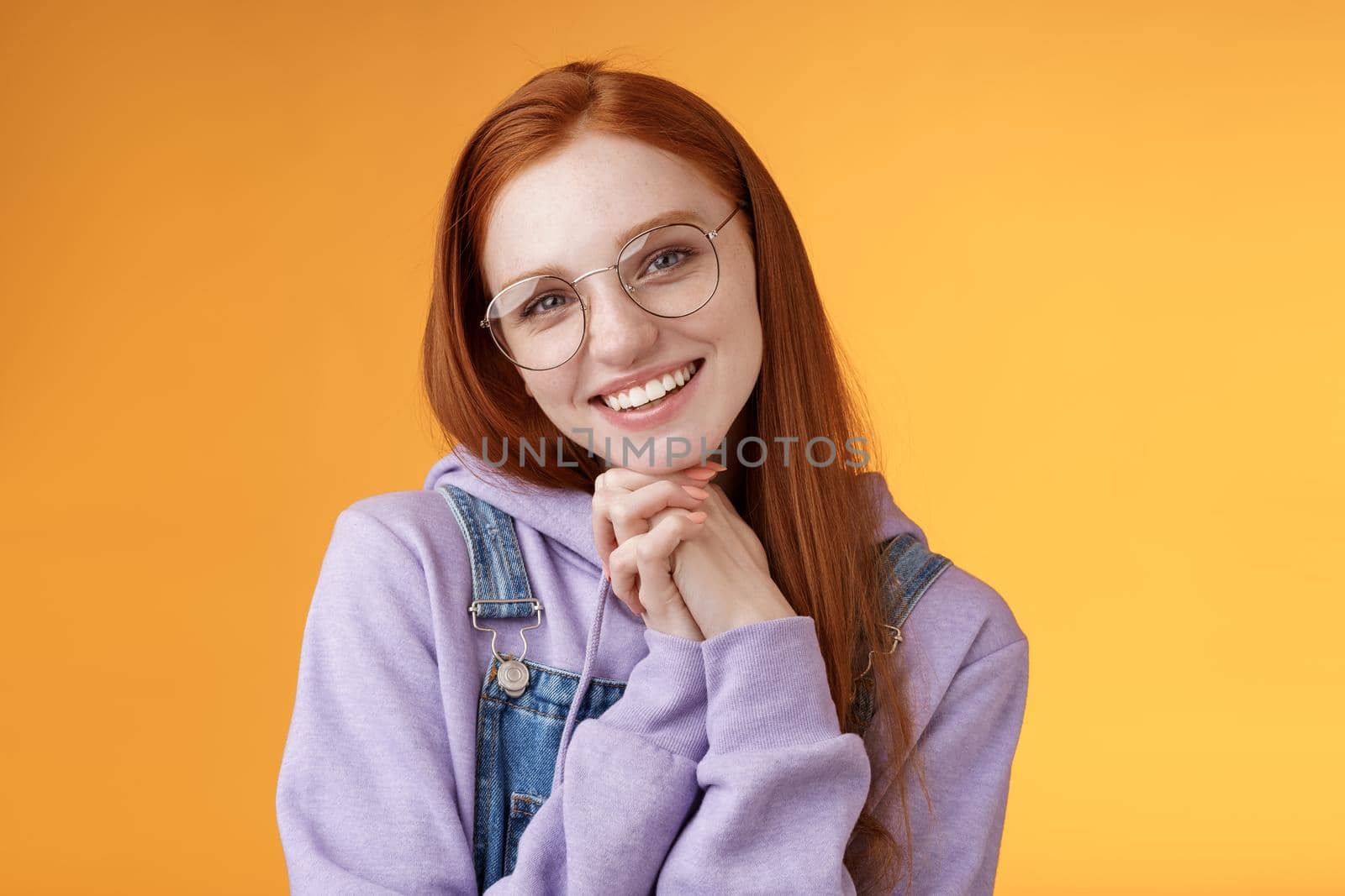 Tender romantic lovely redhead girlfriend leaning palms tilting head cute flirty giggling smiling camera white teeth wearing glasses hoodie overalls near orange background, sensually laughing by Benzoix