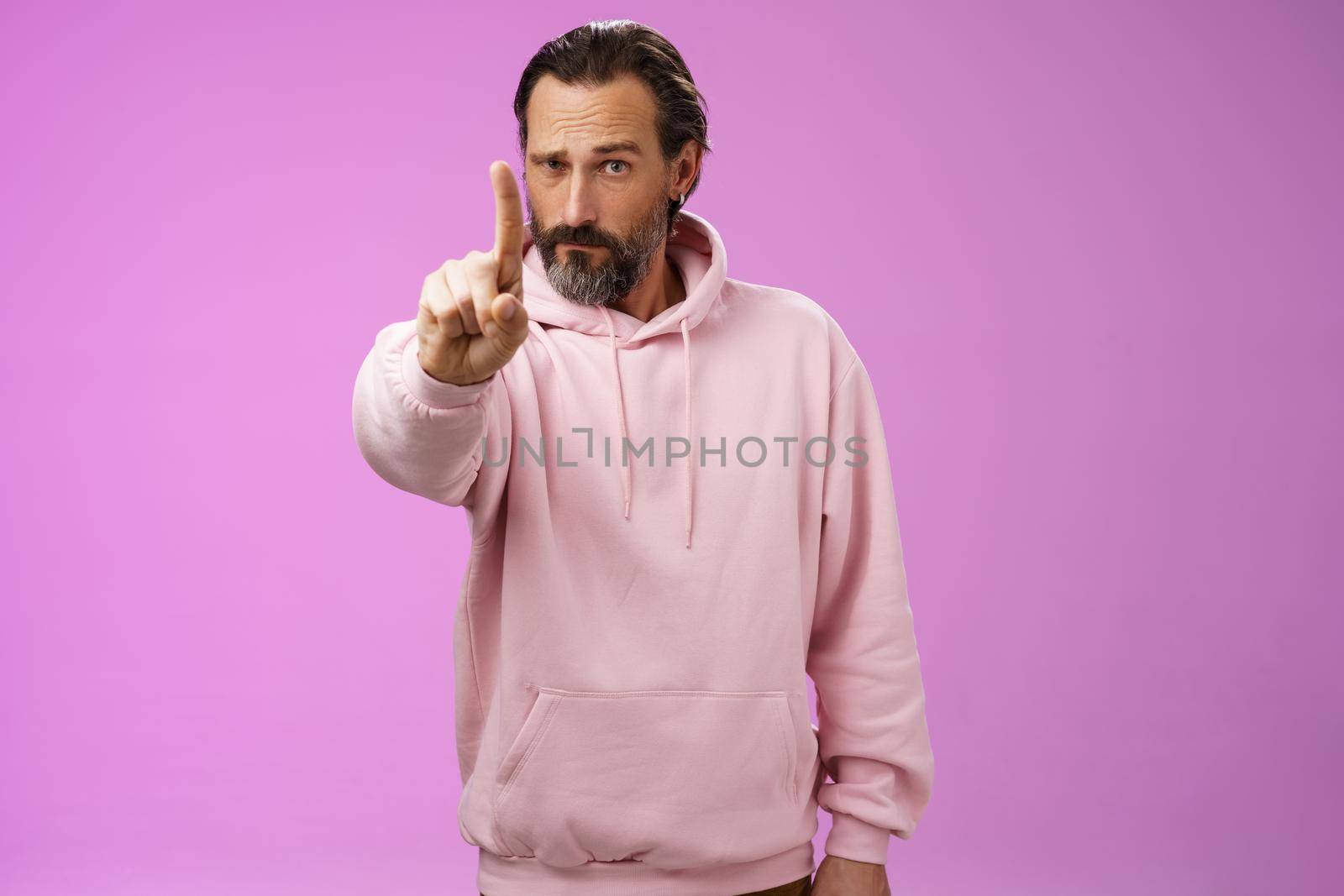 One rule listen. Serious-looking bossy focused determined adult bearded male in pink hoodie extend index finger first number scolding making statement forbid bad behaviour, purple background by Benzoix