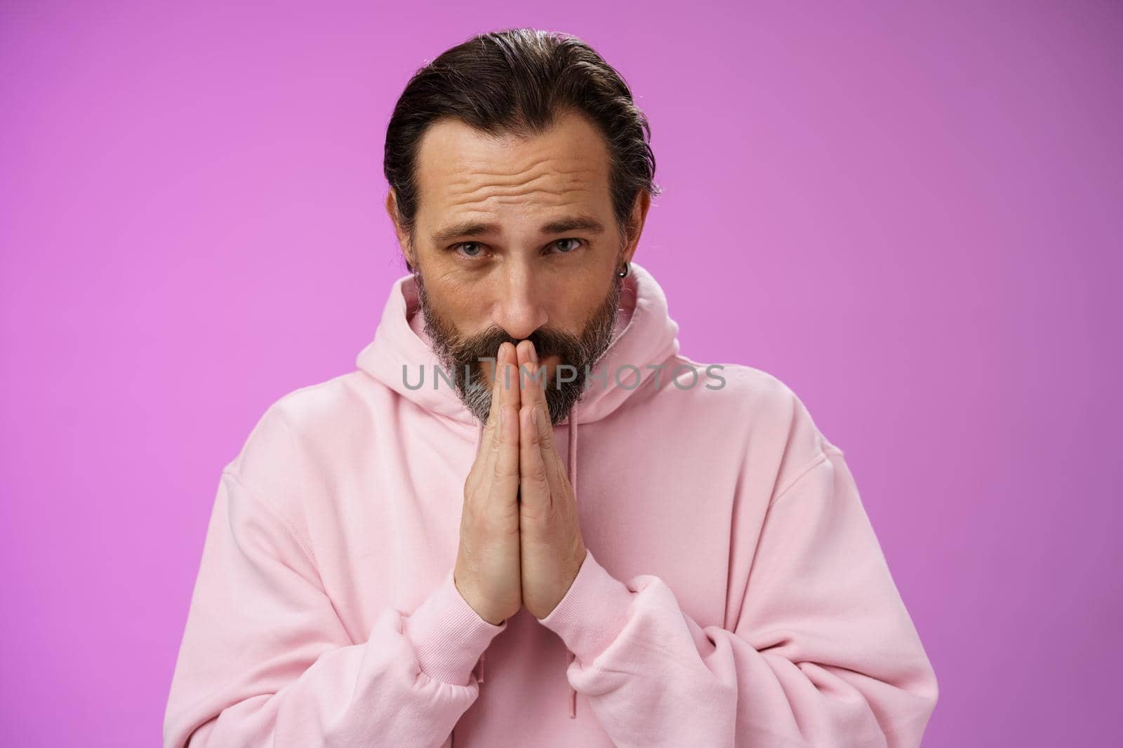 Worried intense serious-looking troubled handsome mature bearded man praying waiting important news nervously looking camera press palms supplicating wish wife alright, standing purple background by Benzoix