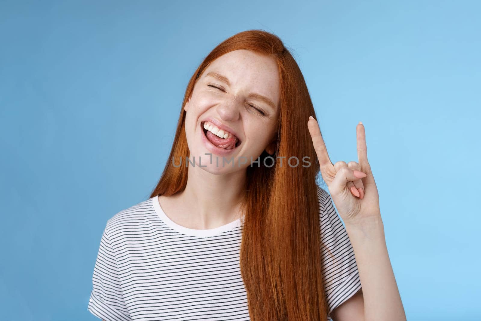 Lifestyle. Happy cheerful carefree chilling redhead teenage girl having fun stick tongue close eyes dancing joyfully show rock-n-roll heavy metal sign enjoy party amusing festival music performance.