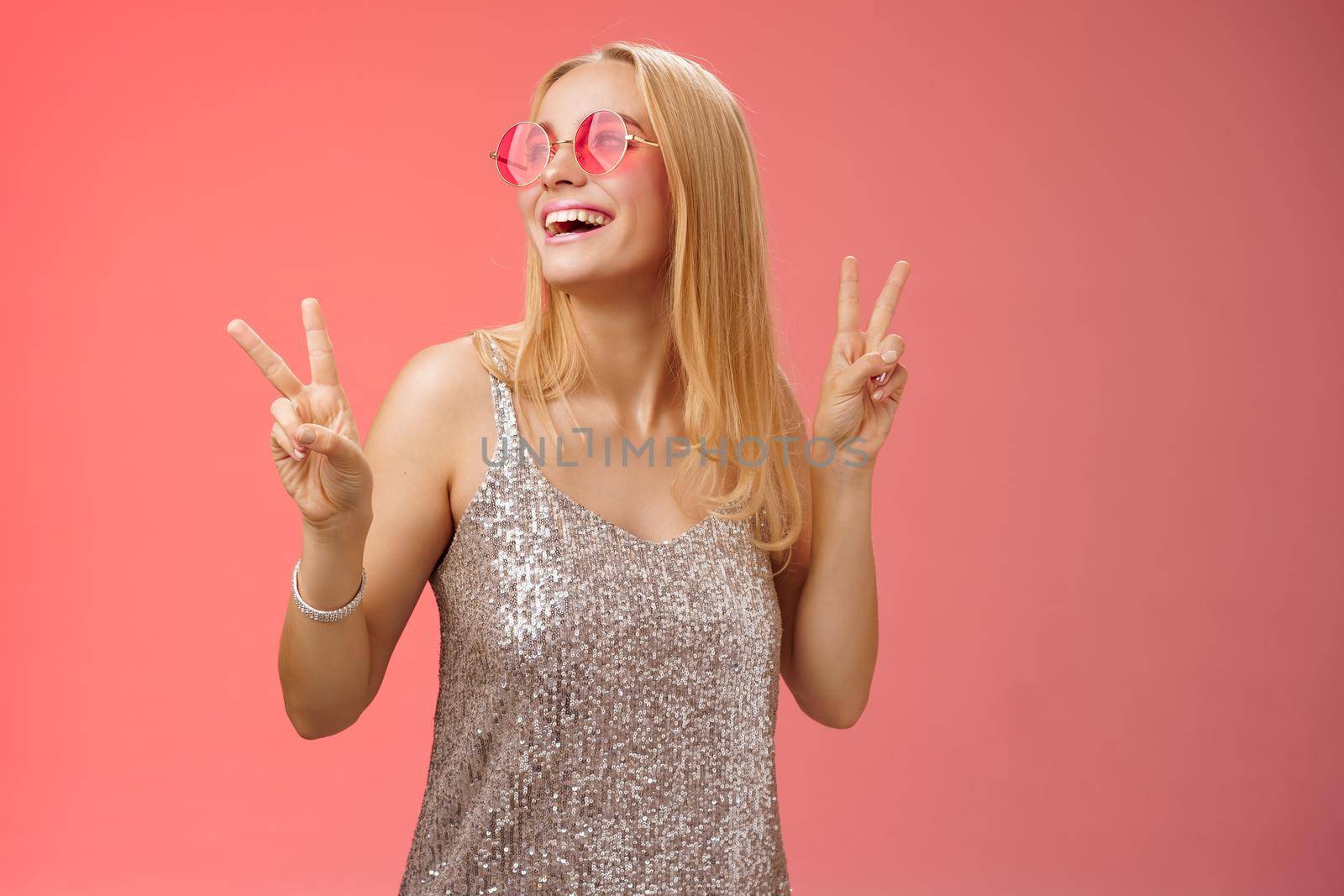 Positive charming european carefree stylish girlfriend having fun dance-floor show victory peace signs look up happily smile in sunglasses glamour glittering dress enjoy celebration, red background by Benzoix