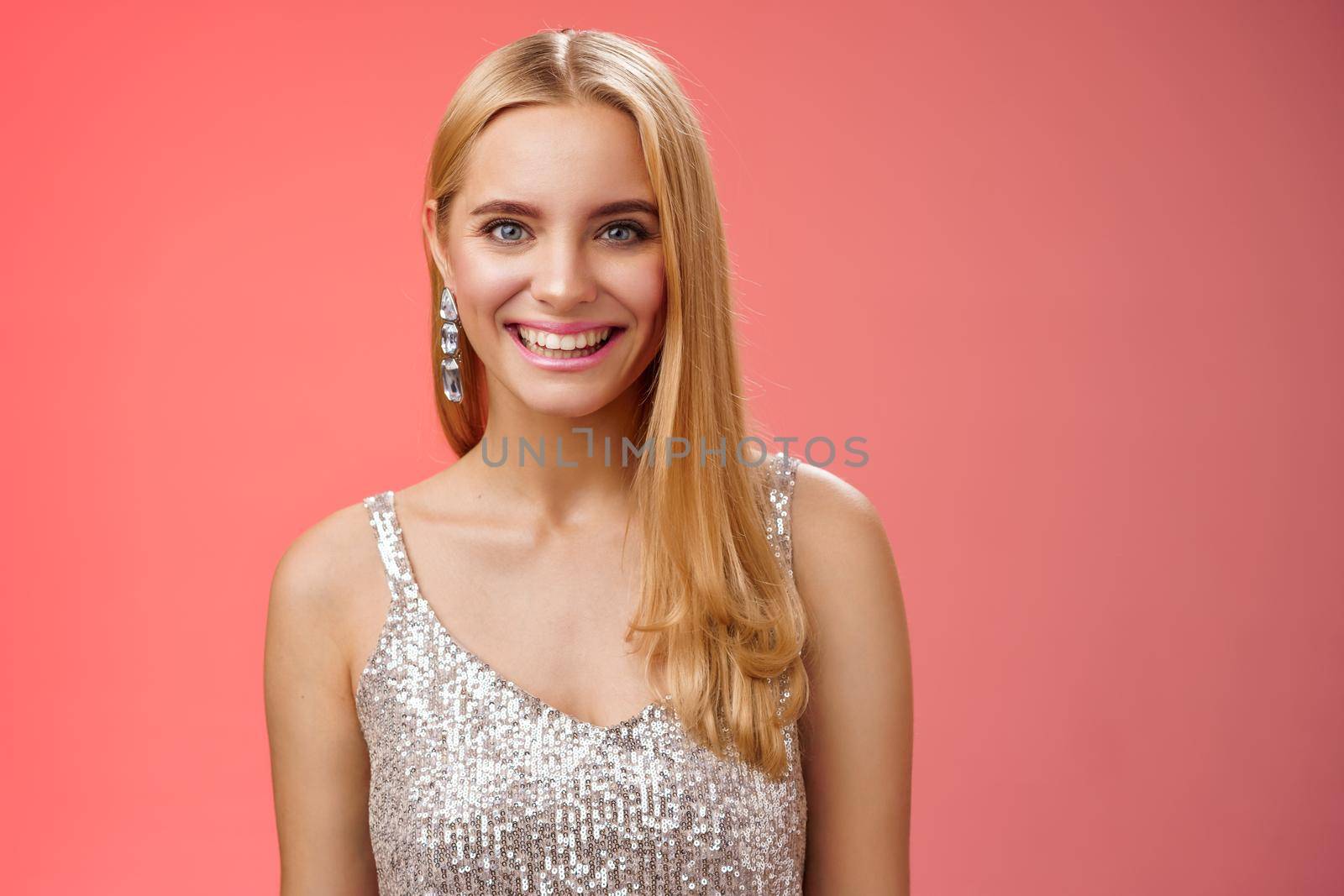 Charming glamour fabulous adult 25s blond woman in elegant silver dress shiny earrings smiling happily take part interesting conversation talking look friendly grinning, standing red background.