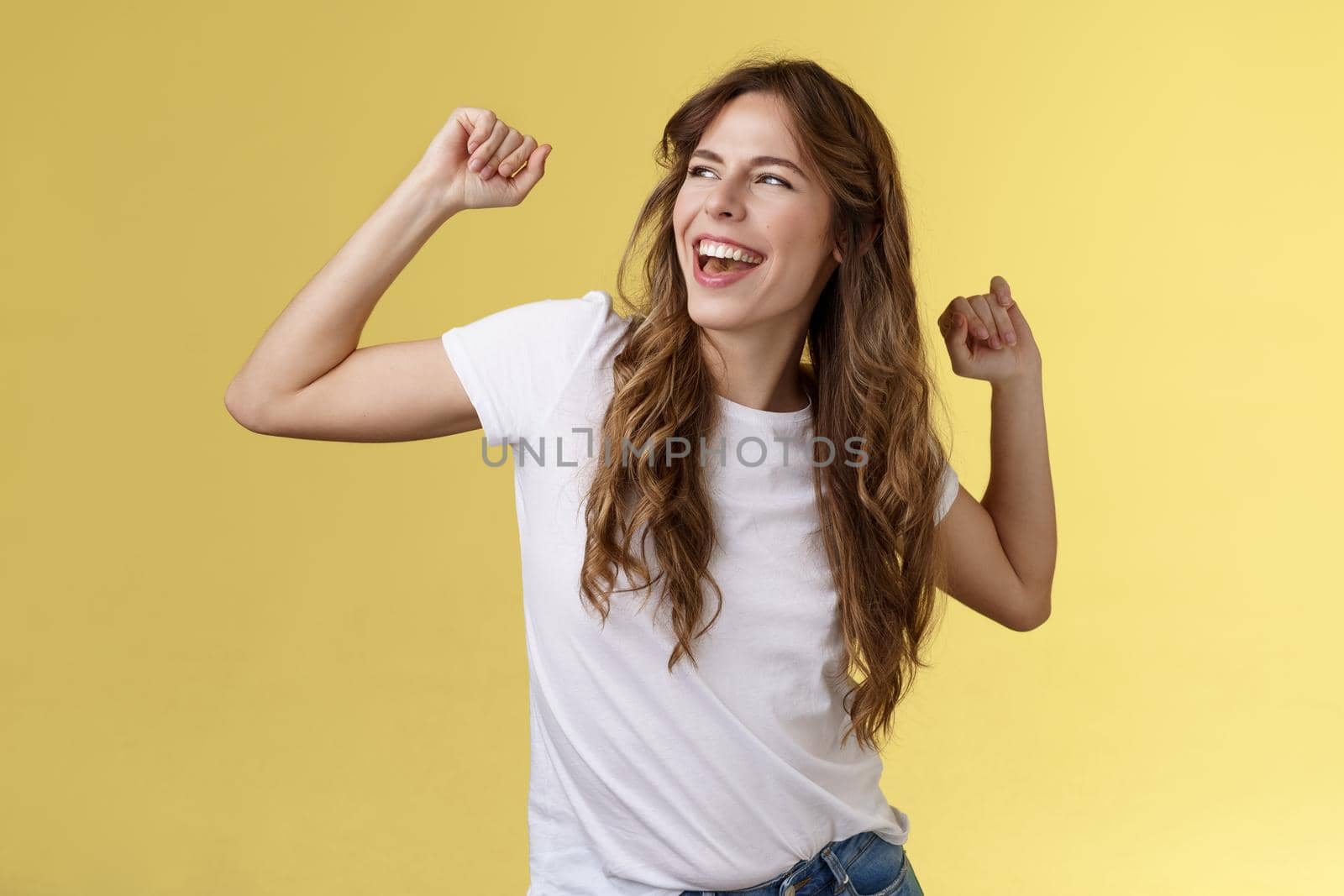 Yeah let perfect summer days behind. Daring good-looking happy charismatic young woman curly haircut gaze left pleased carefree having fun raise hands up celebratory victory winning success.