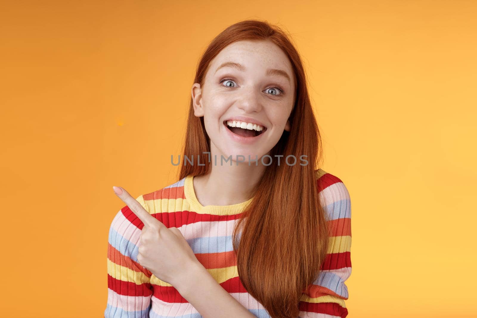 Amused carefree thrilled emotional redhead female fan adore talking favorite movie pointing upper left corner fascinated smiling broadly happy delighted attend incredible party, orange background by Benzoix
